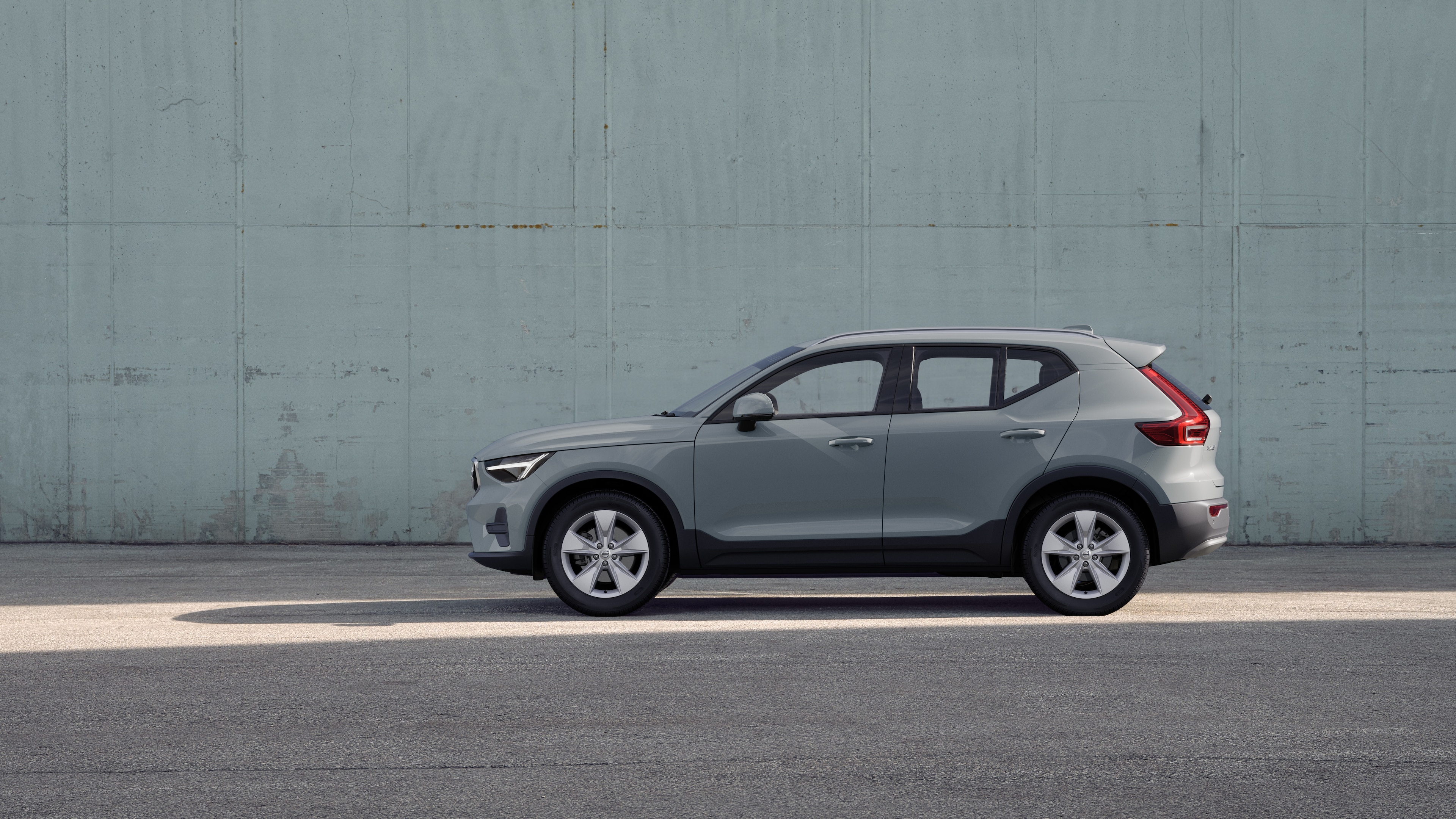 Volvo car, side view, parked against a plain concrete wall background.