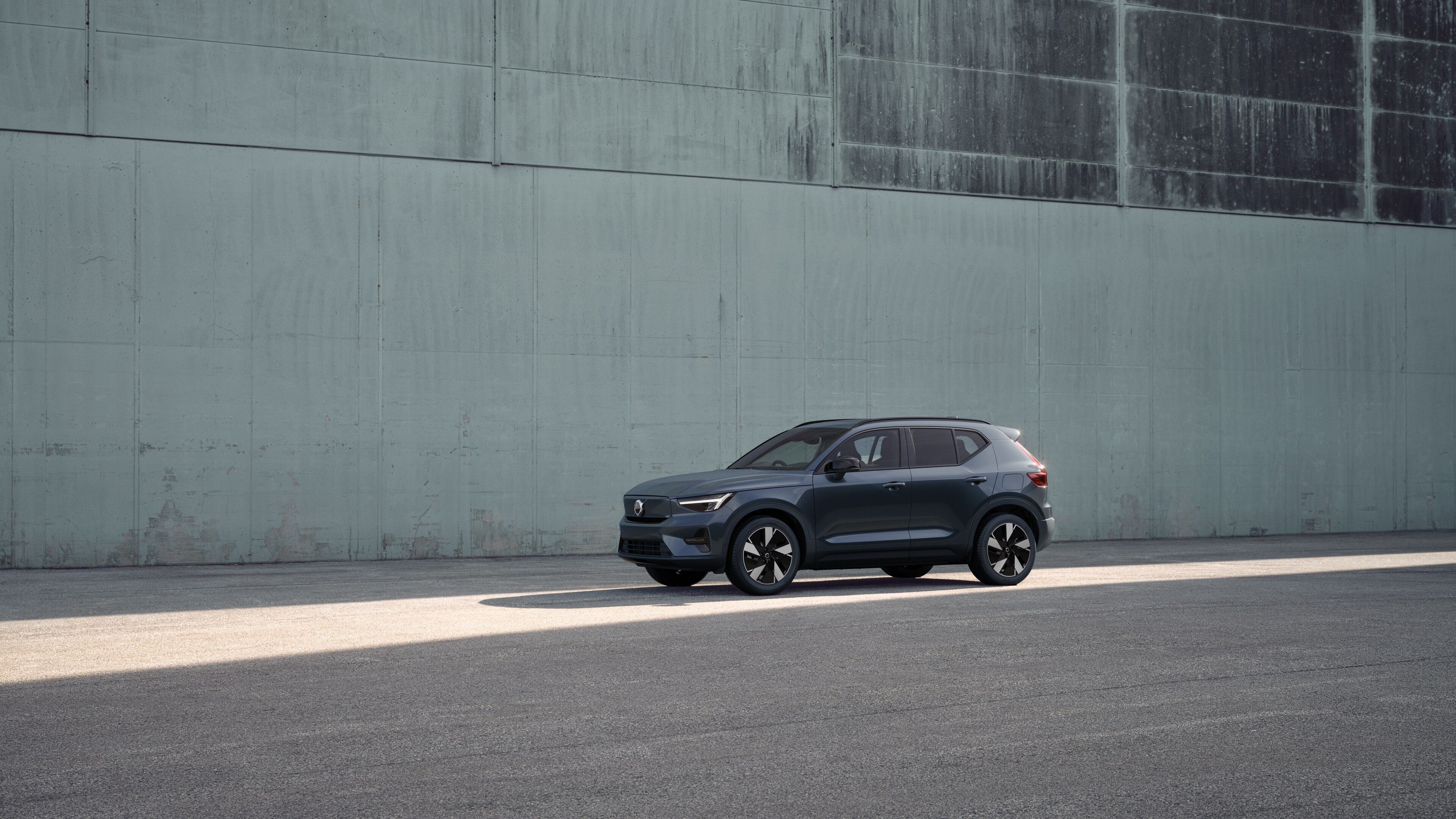 Volvo car exterior in three-quarter view against an industrial concrete wall background.