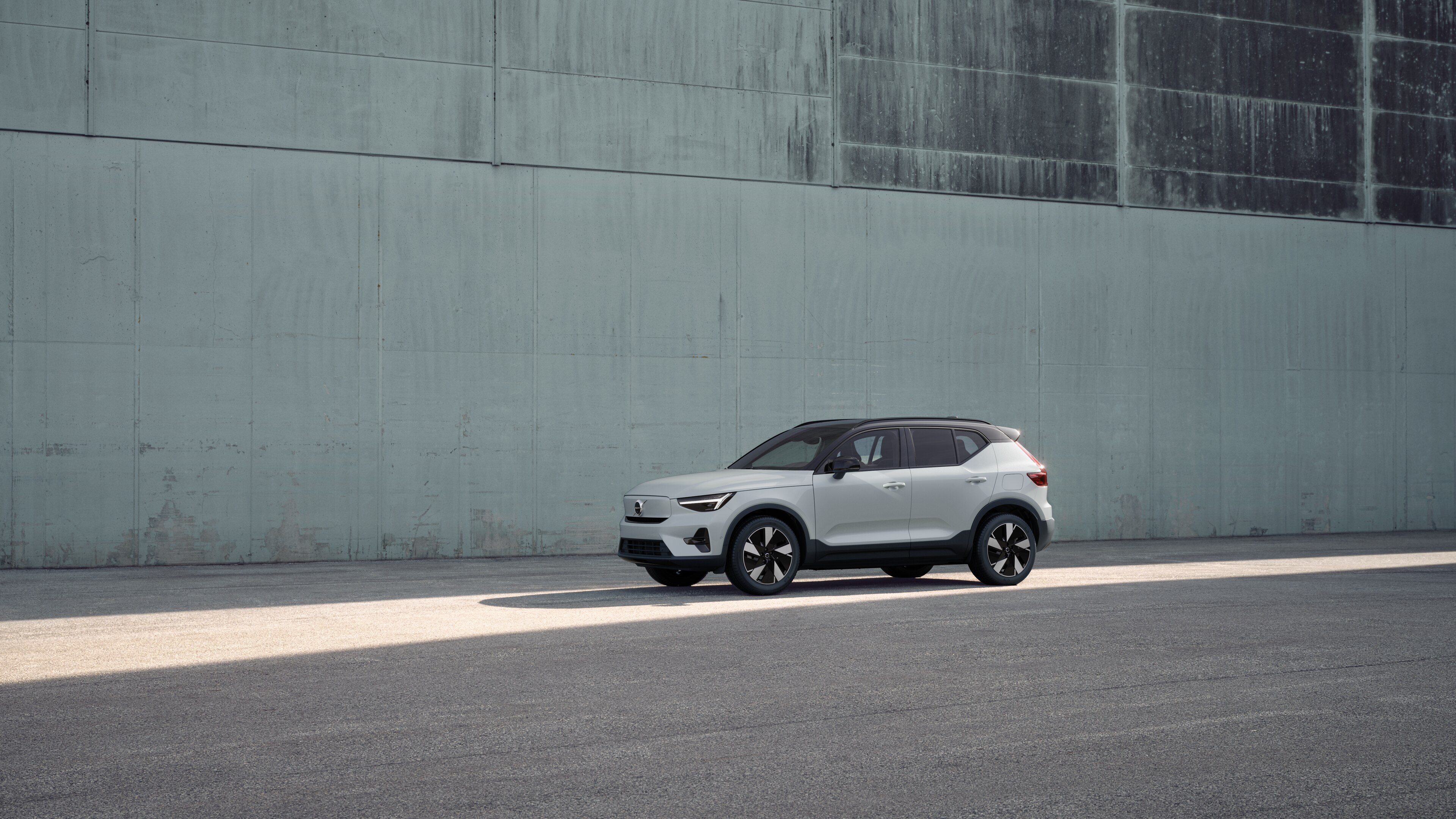Vue de trois quarts de l’extérieur d’une Volvo sur un fond de mur industriel en béton.