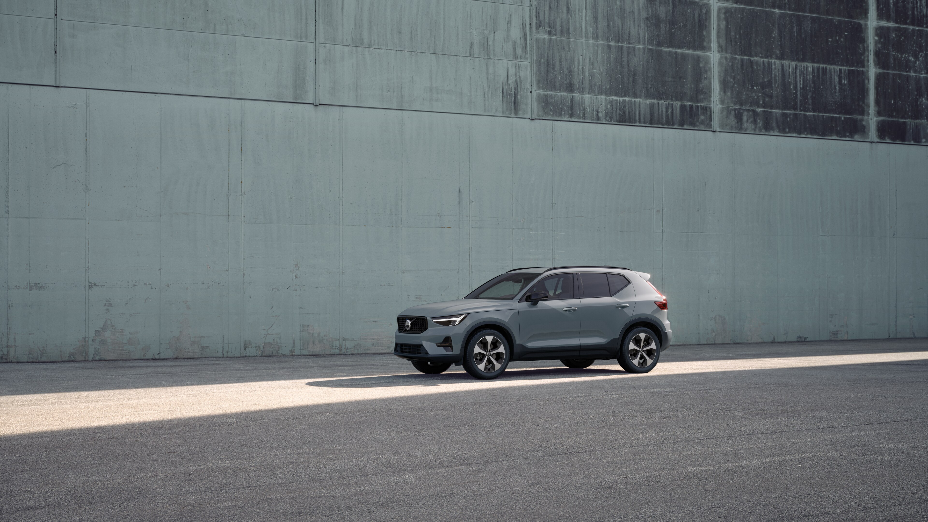 Exterieur van een Volvo in driekwart aanzicht tegen een achtergrond van een industriële betonnen muur.