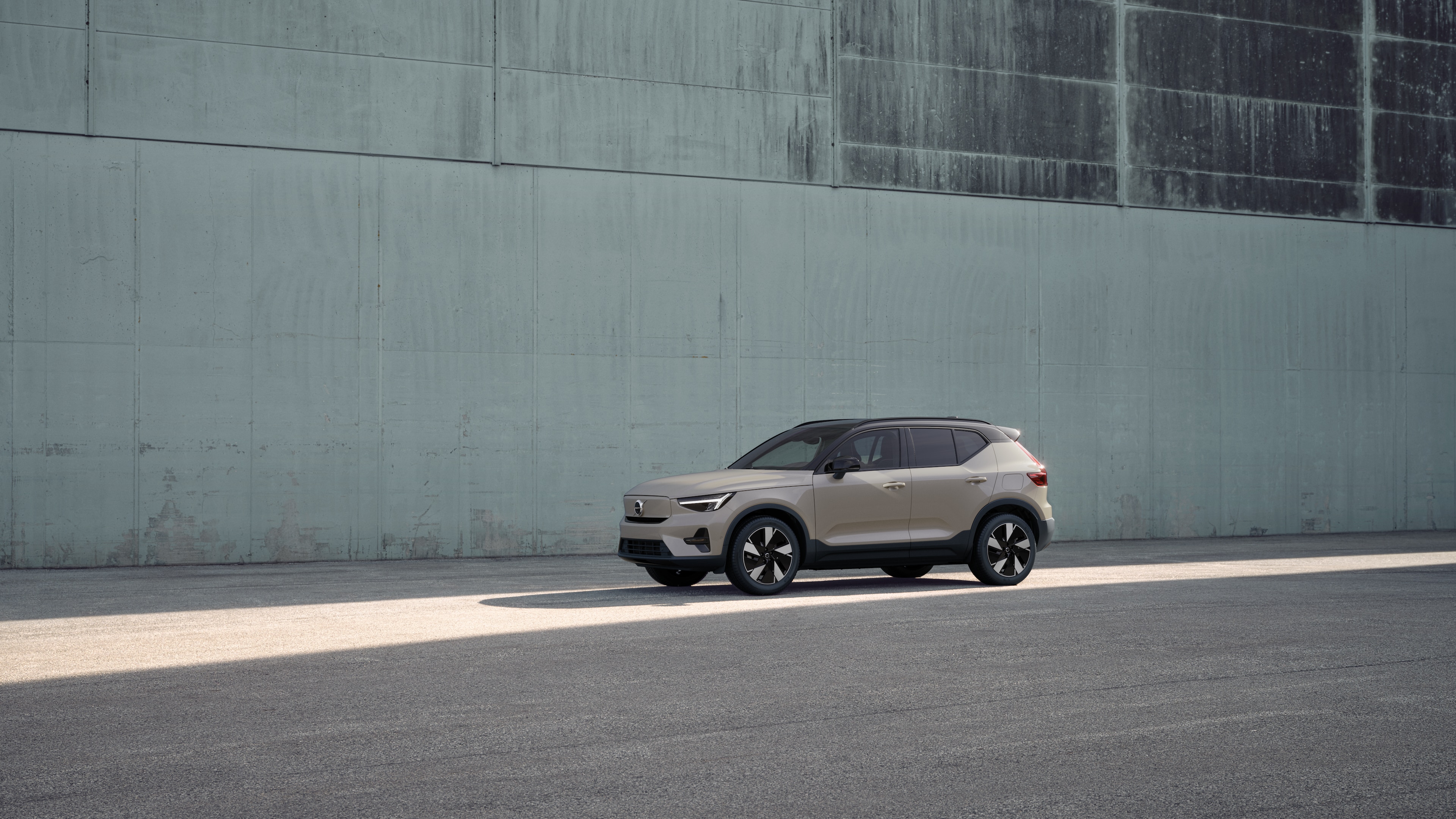 Exterieur van een Volvo in driekwart aanzicht tegen een achtergrond van een industriële betonnen muur.