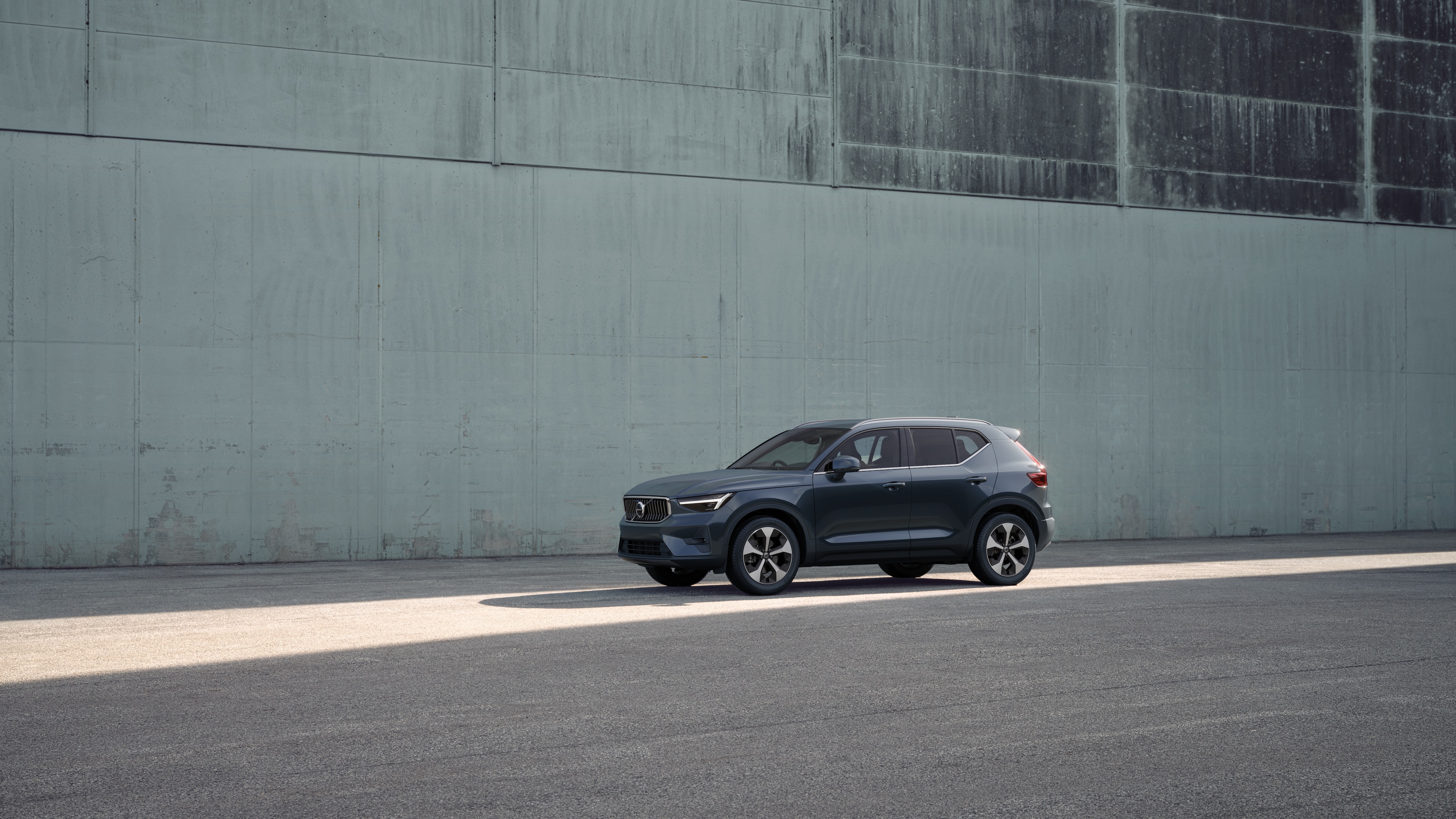 Volvo car exterior in three-quarter view against an industrial concrete wall background.