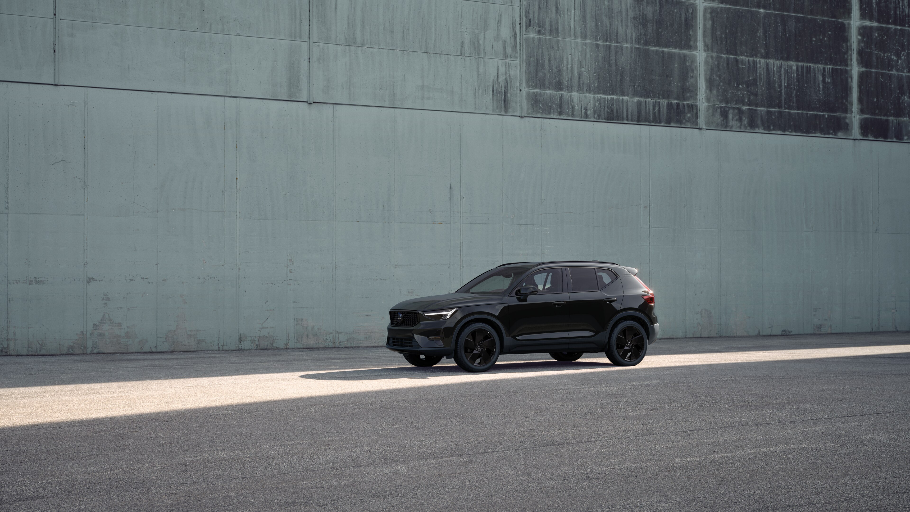 Extérieur d’une Volvo vue de trois quarts sur un fond de mur industriel en béton.
