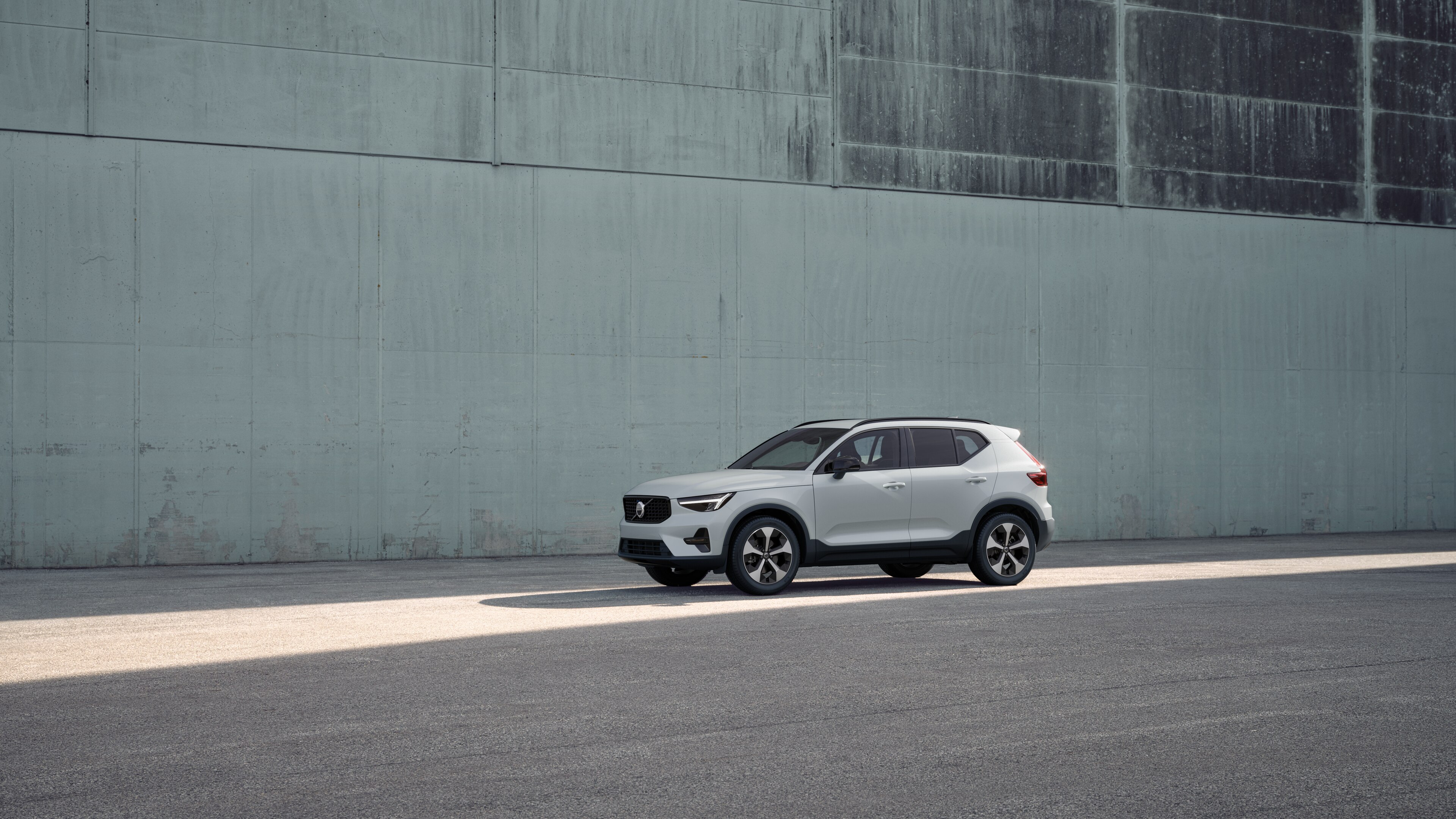 Vue de trois quarts de l’extérieur d’une Volvo sur un fond de mur industriel en béton.