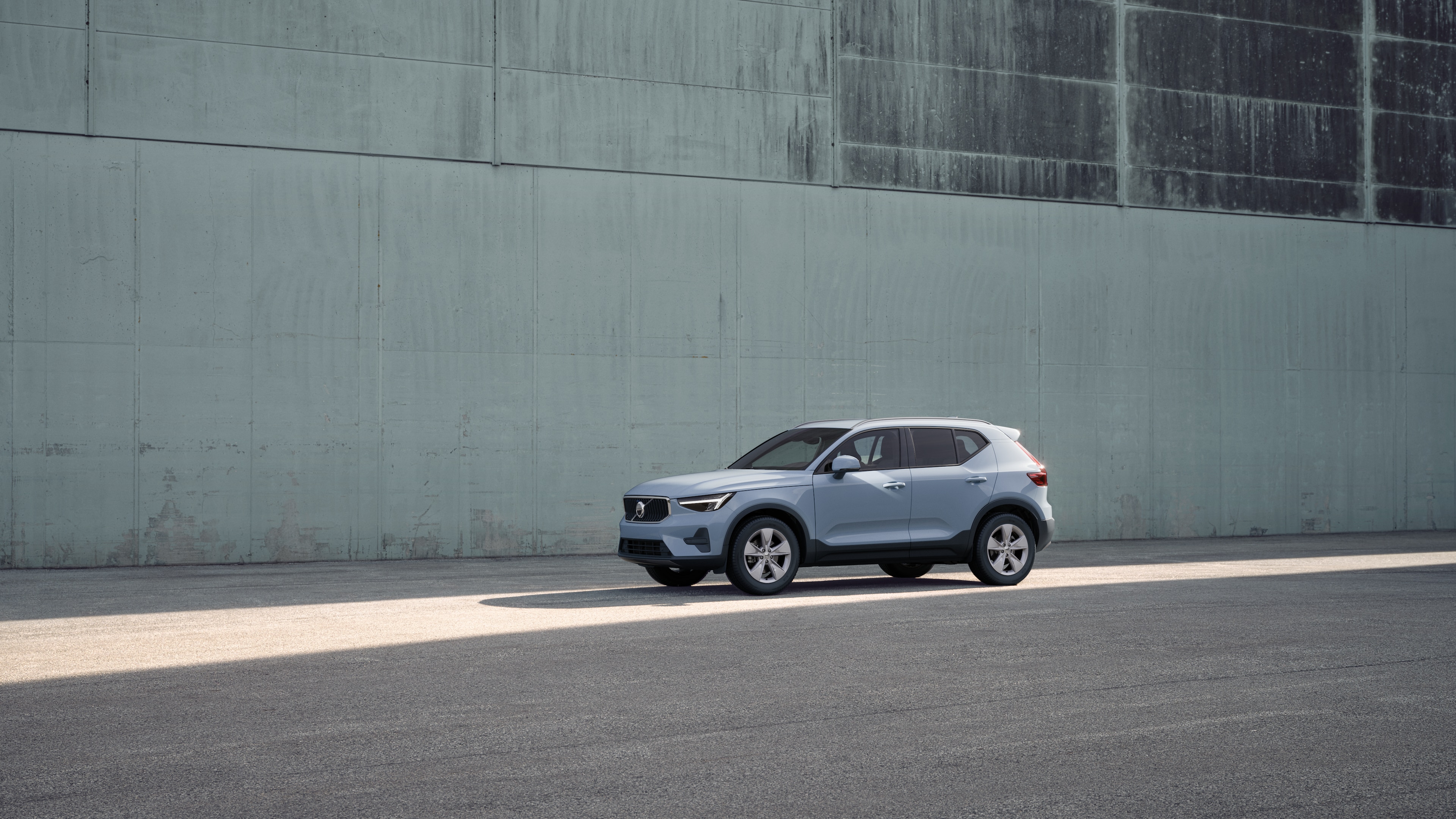 Exteriér vozidla Volvo v trojštvrtinovom pohľade na priemyselnú betónovú stenu.