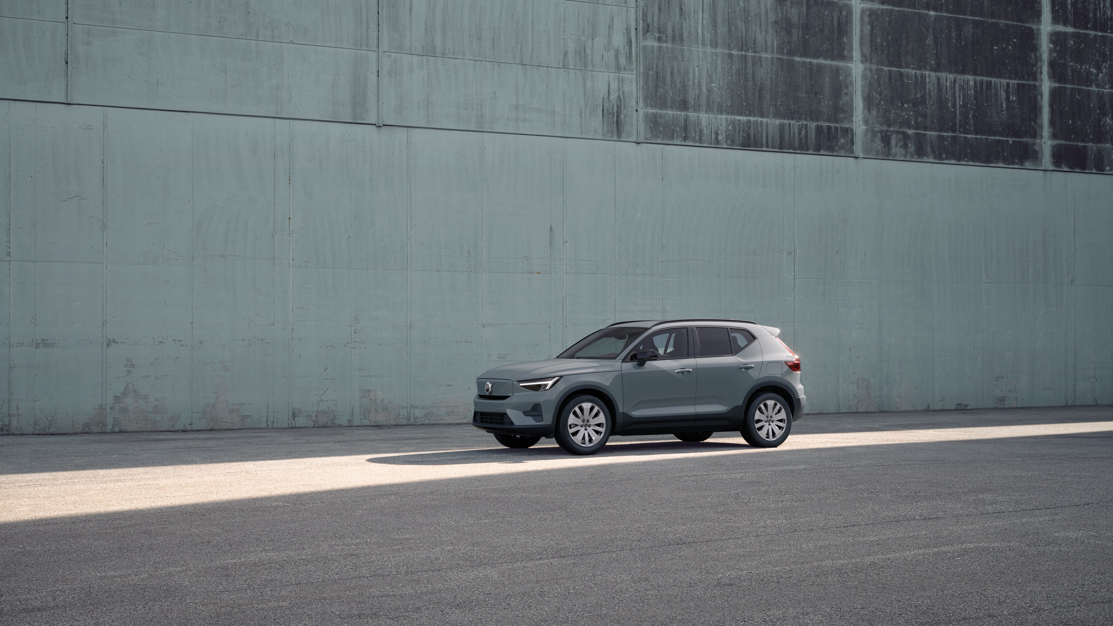 Extérieur d’une Volvo vue de trois quarts sur un fond de mur industriel en béton.