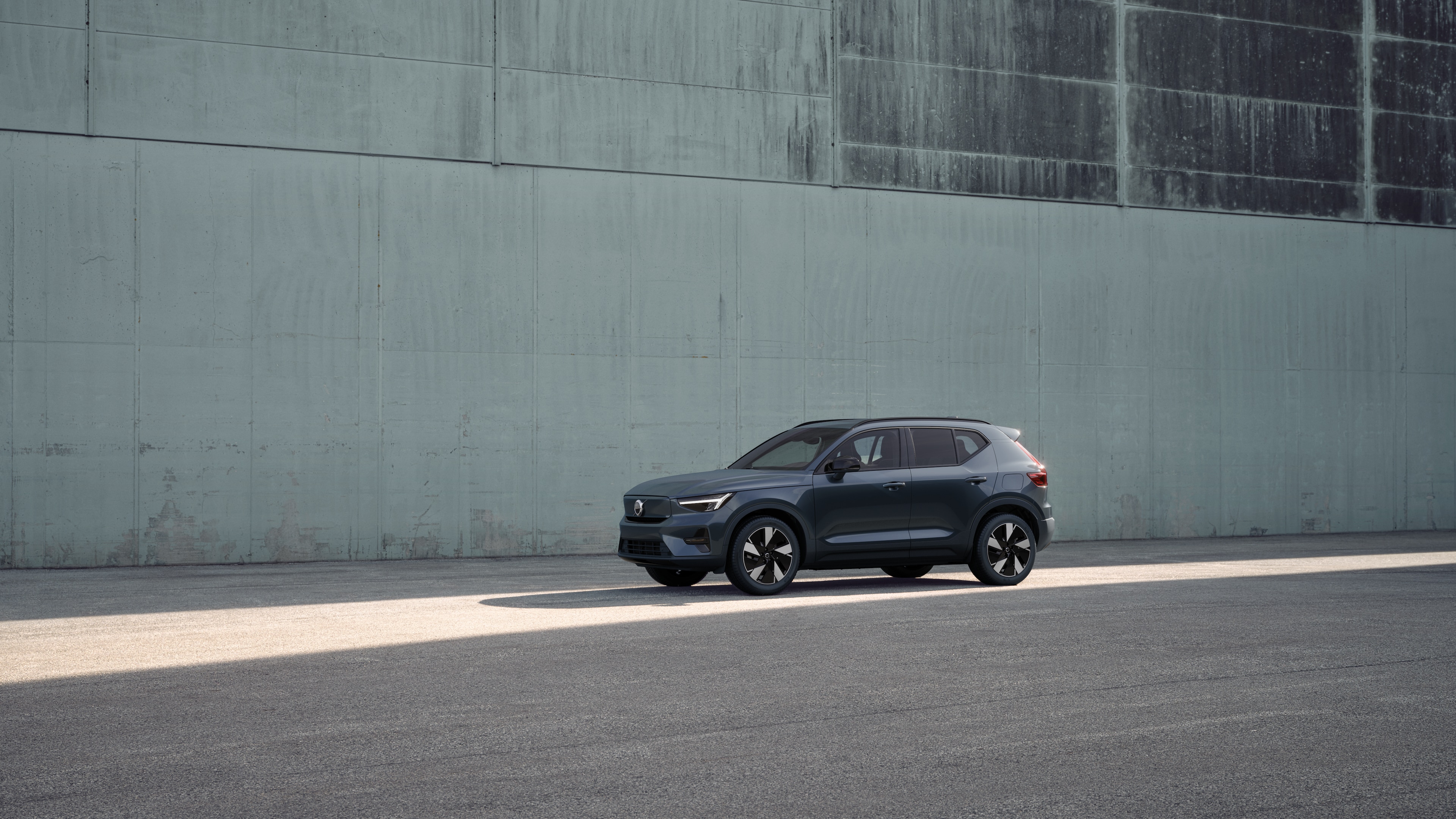 Exterior do carro Volvo em vista de três quartos contra um fundo de parede de concreto industrial.