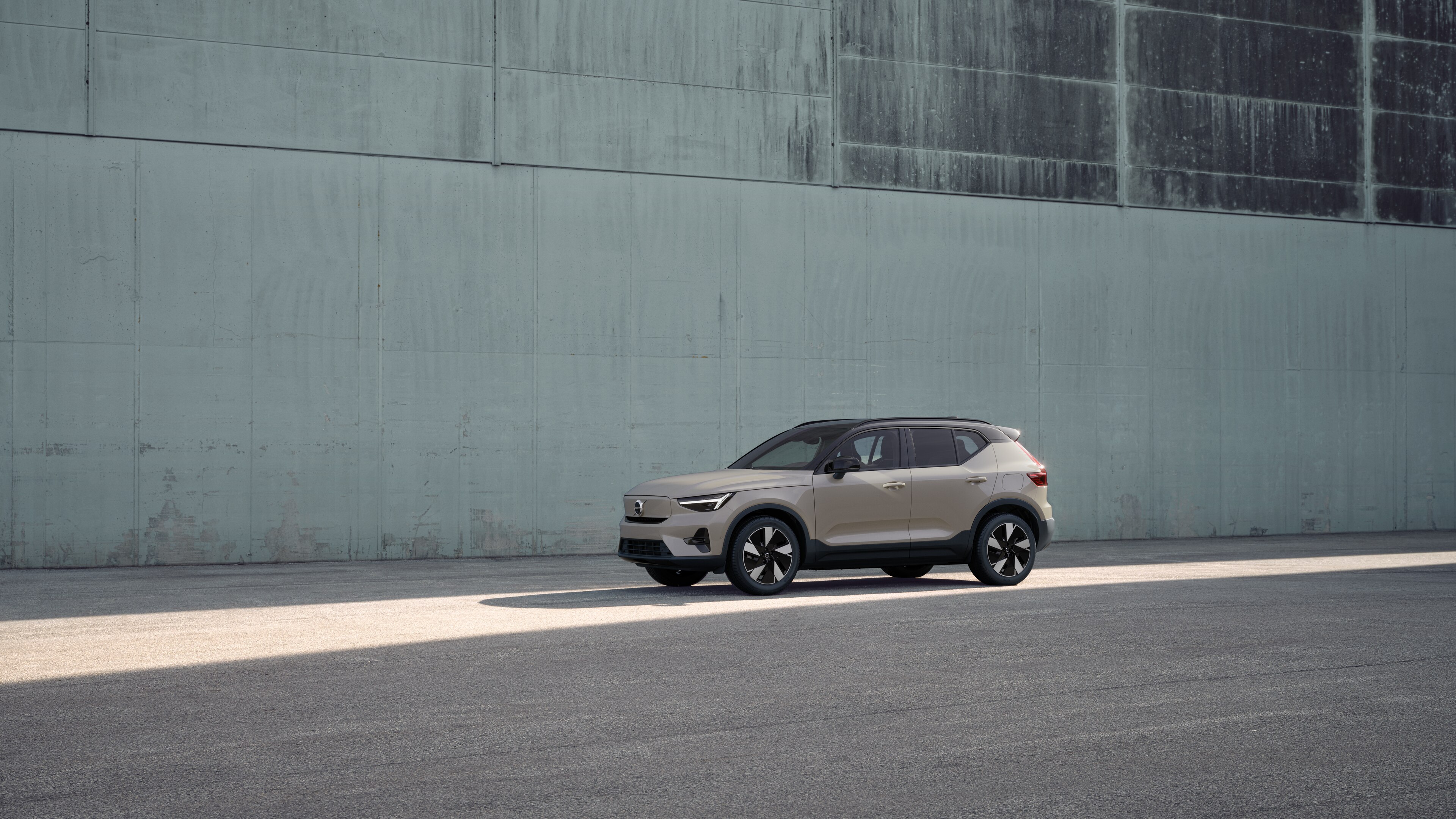 Vue de trois quarts de l’extérieur d’une Volvo sur un fond de mur industriel en béton.