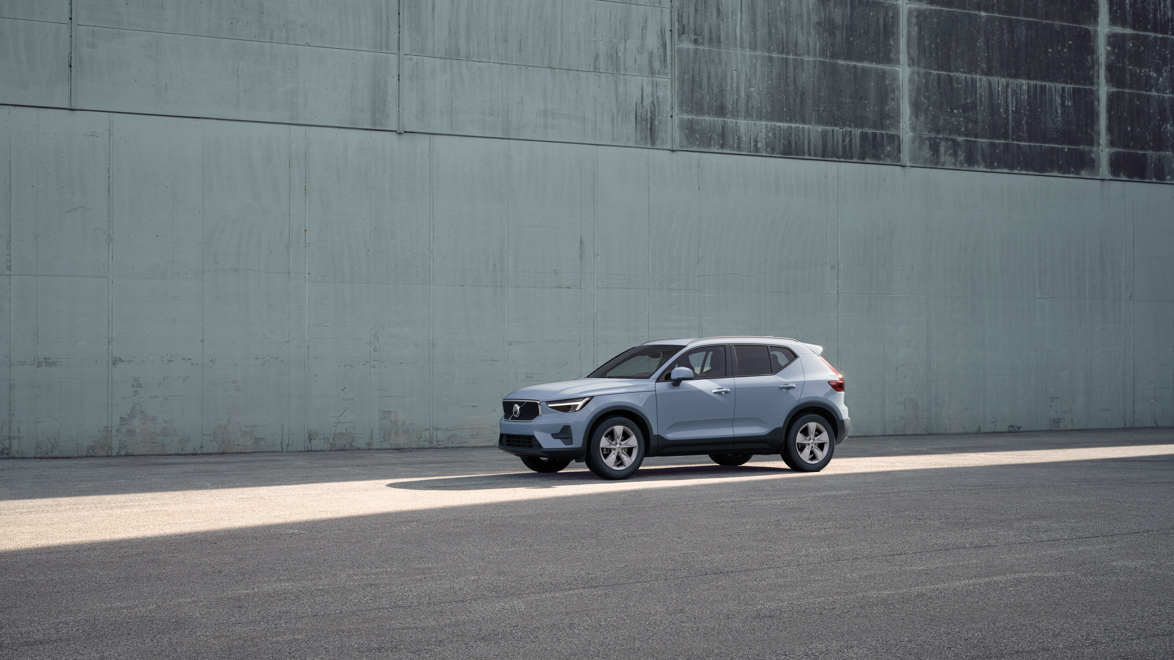 Volvobilens exteriör i trekvartsvy mot en industriell betongväggsbakgrund.