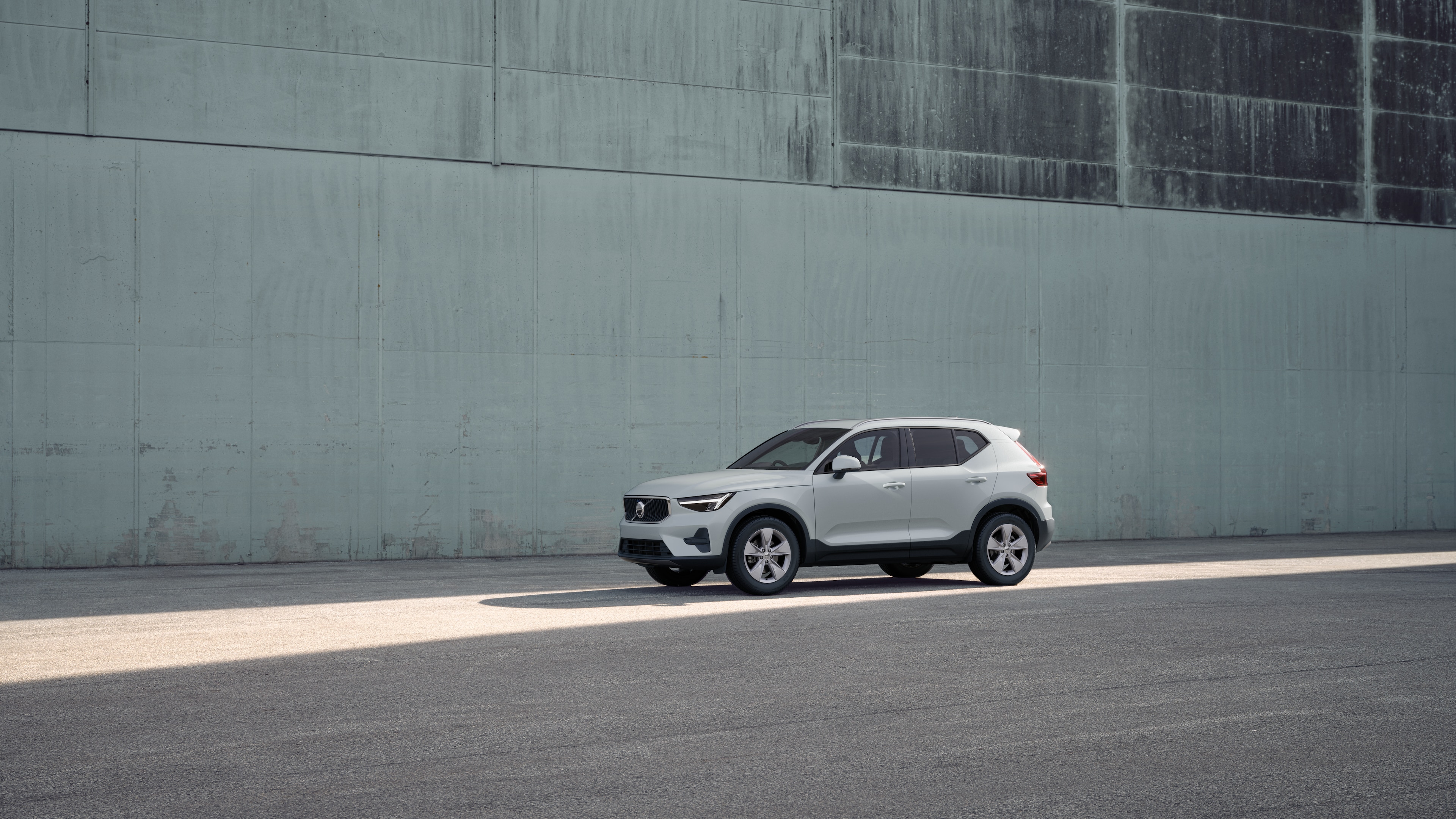 Volvo car exterior in three-quarter view against an industrial concrete wall background.