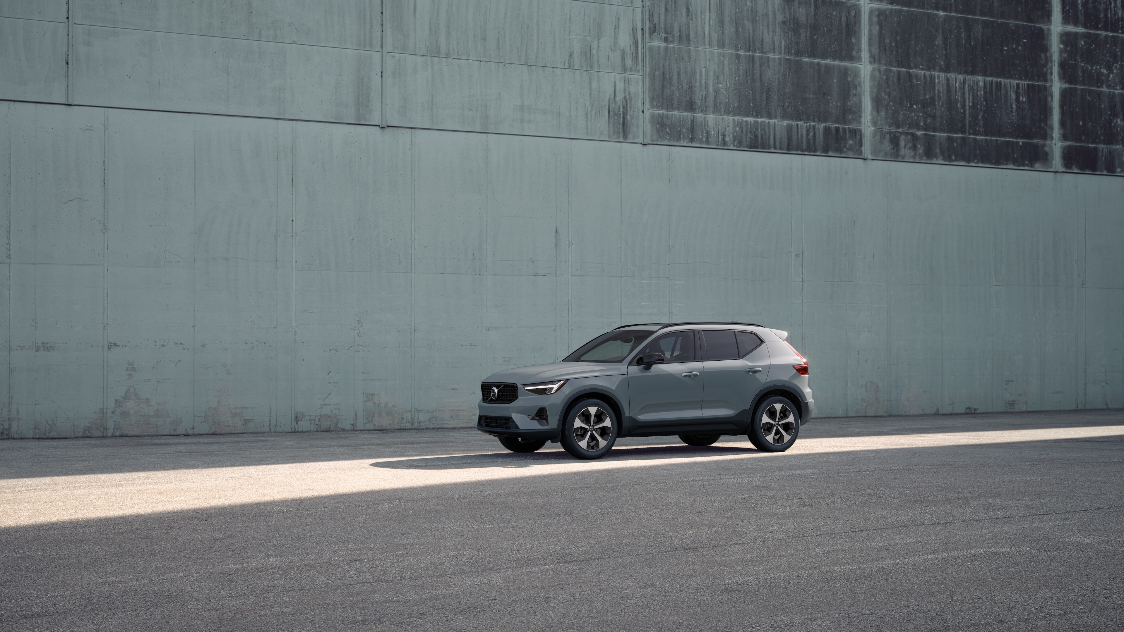 Exterior del vehículo Volvo en vista de tres cuartos sobre un fondo de muro de hormigón industrial.