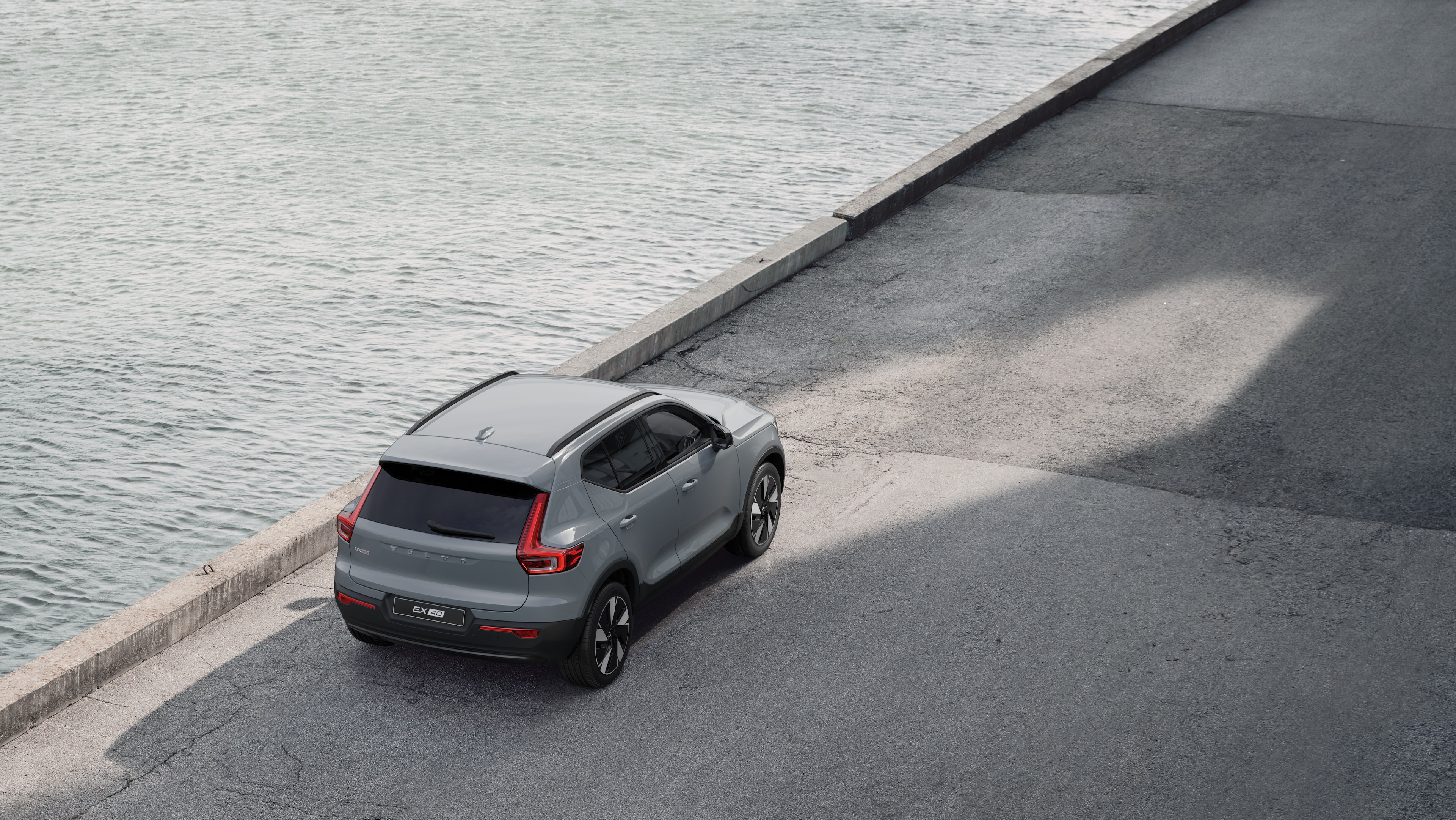 Vue arrière d’une Volvo garée dans une rue calme au bord de l’eau, avec une passerelle pavée et de l’eau en arrière-plan.