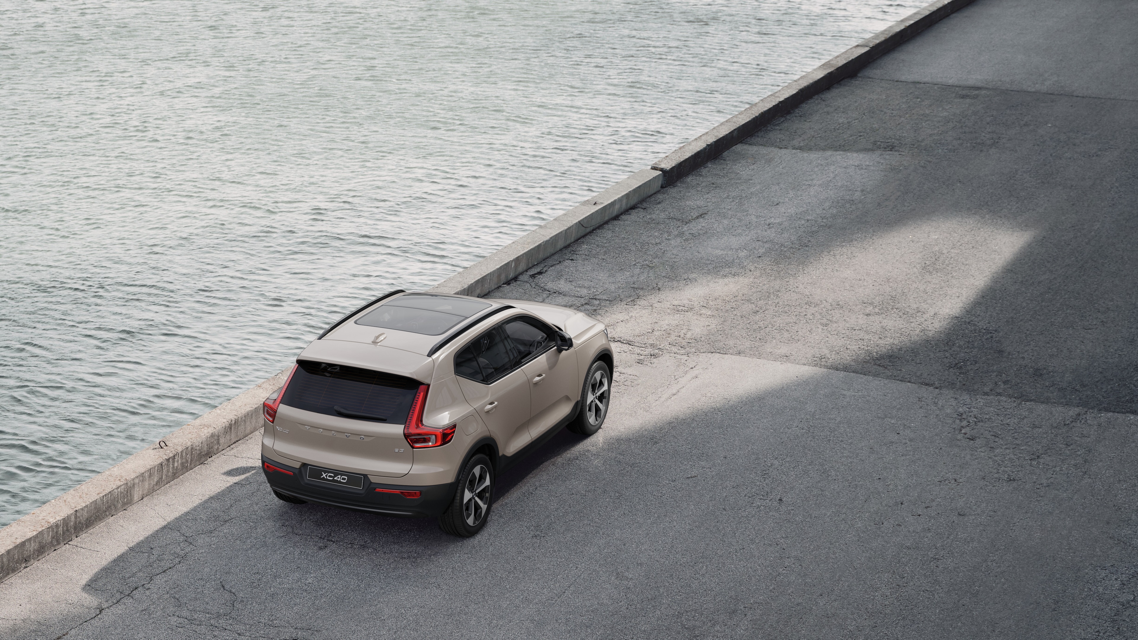Vue arrière d’une Volvo garée dans une rue calme au bord de l’eau, avec une passerelle pavée et de l’eau en arrière-plan.