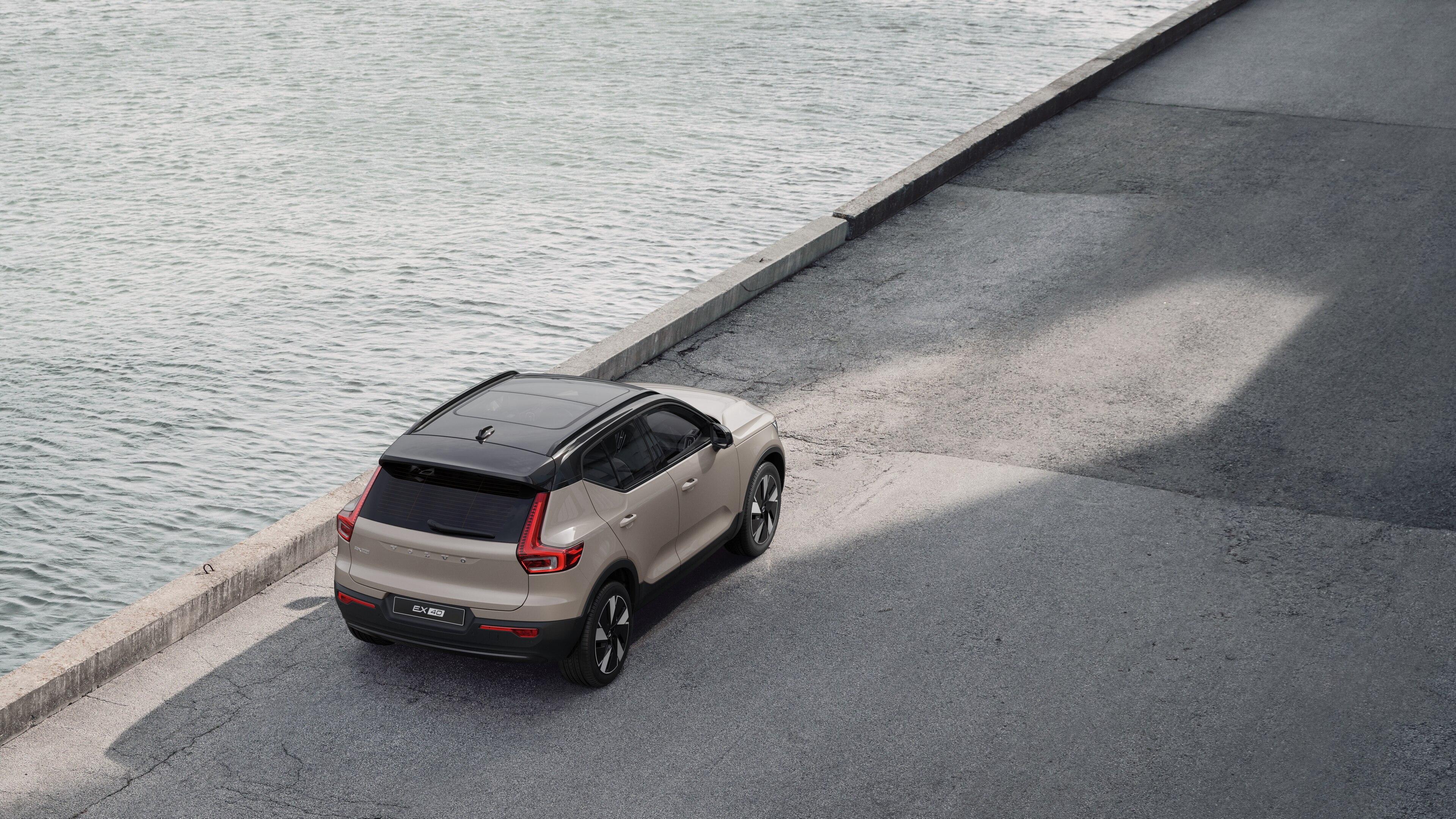 Vue arrière d’une Volvo garée dans une rue calme au bord de l’eau, avec une allée pavée et de l’eau en arrière-plan.
