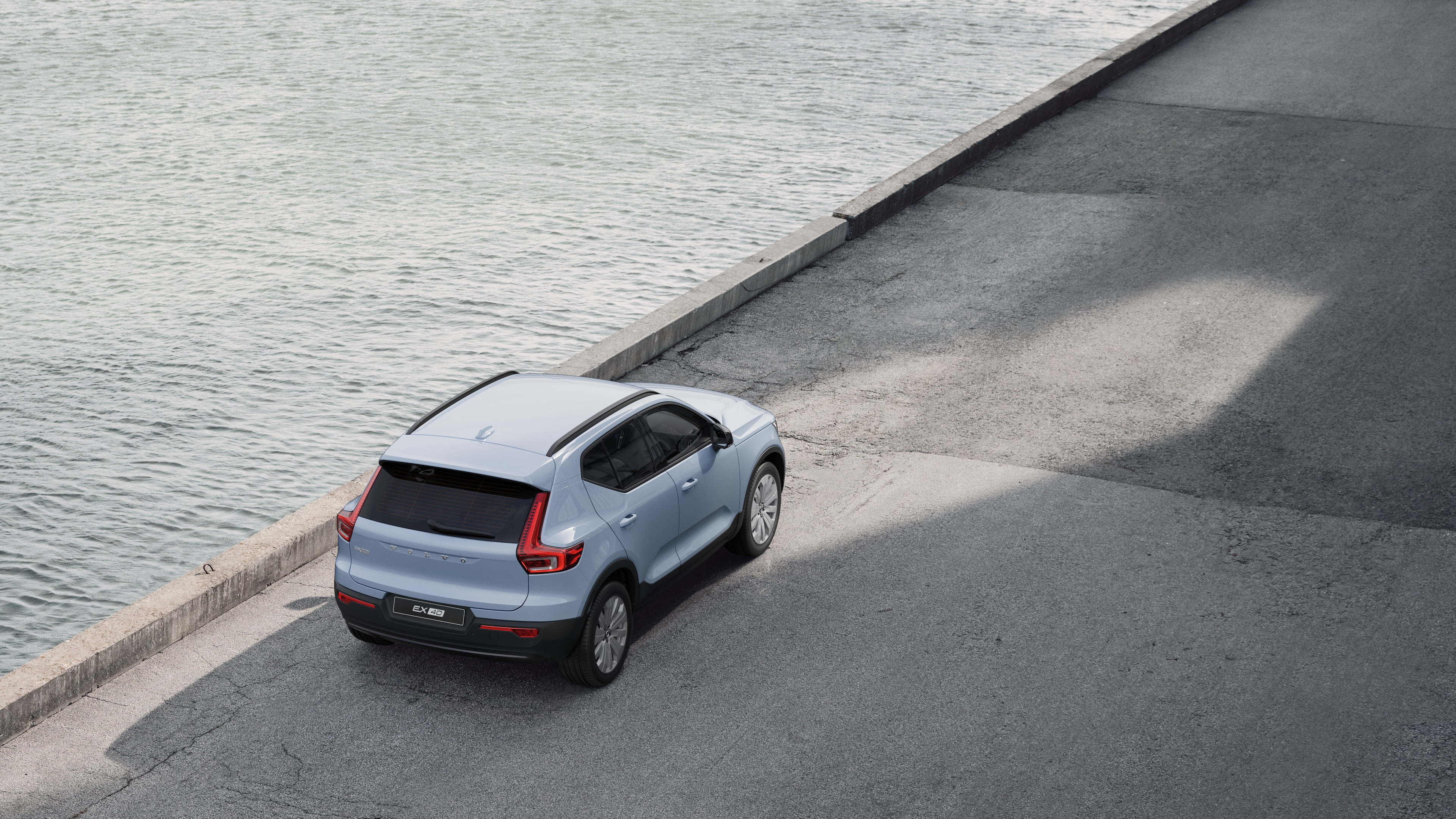 Heckansicht eines Volvo, der in einer ruhigen Straße am Wasser geparkt ist, mit einem gepflasterten Gehweg und Wasser im Hintergrund.