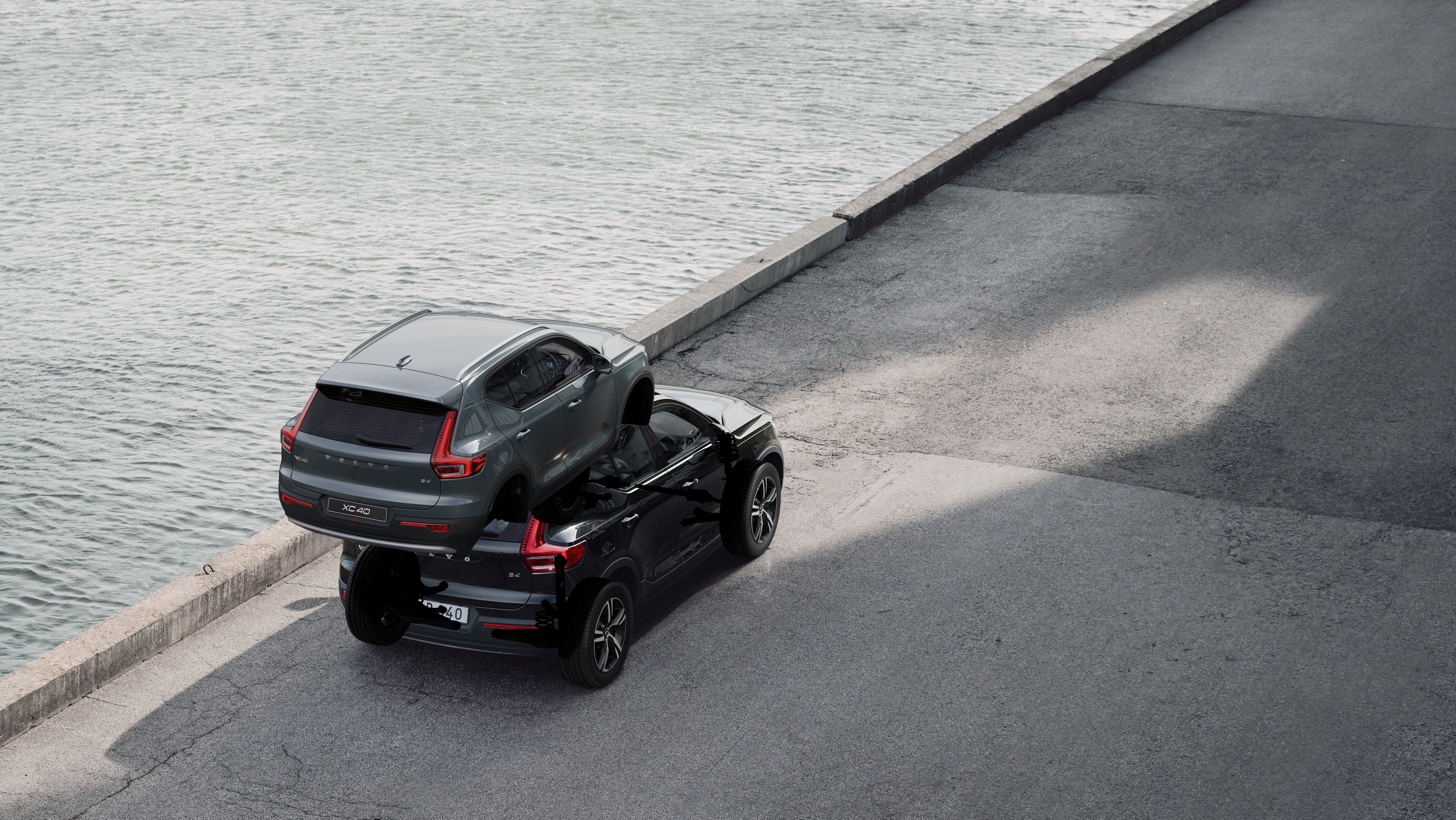 Volvo car rear view parked on quiet street beside water, with a paved walkway and water as the background.