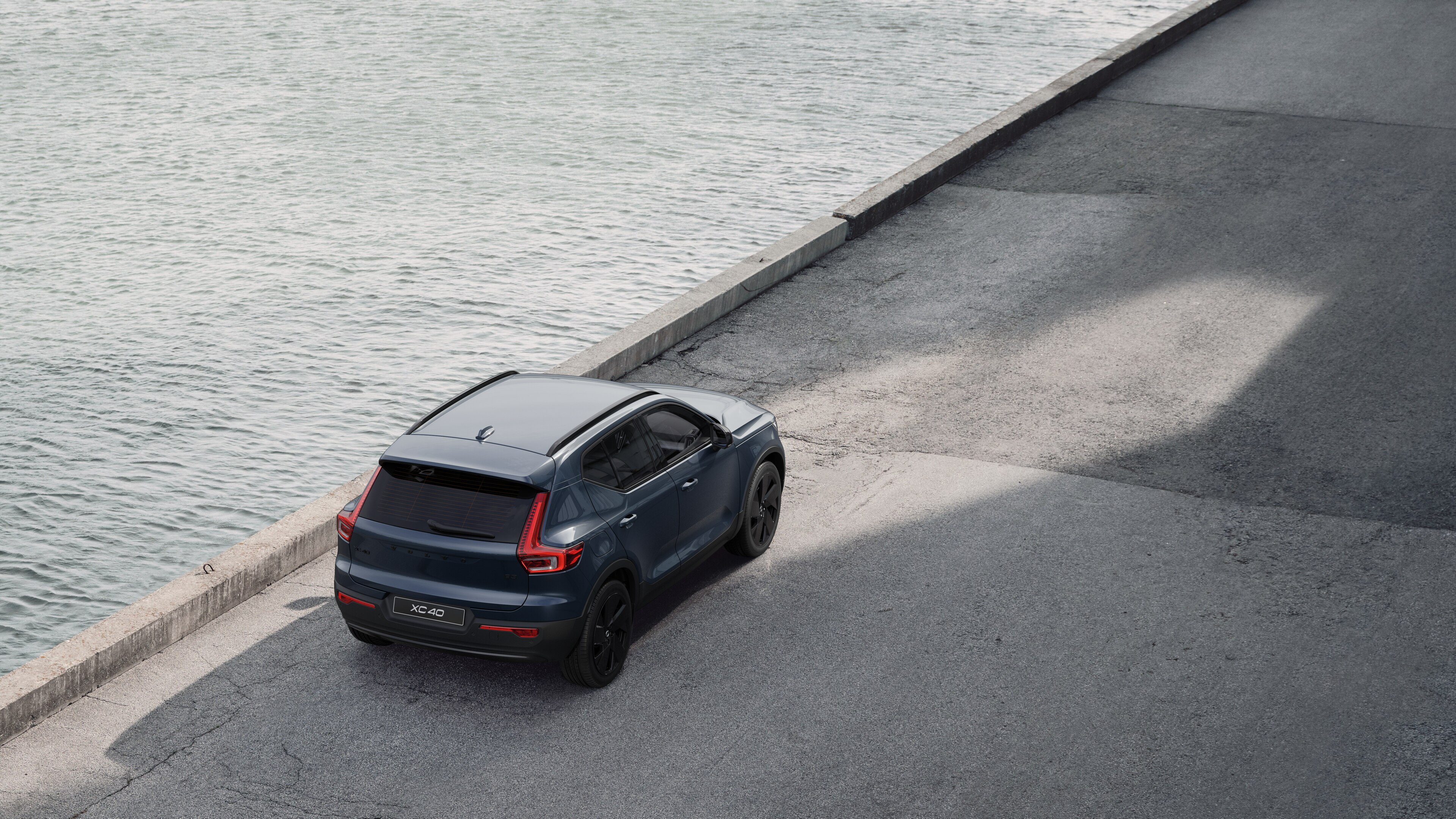 Heckansicht eines Volvo, der in einer ruhigen Straße am Wasser geparkt ist, mit einem gepflasterten Gehweg und Wasser im Hintergrund.