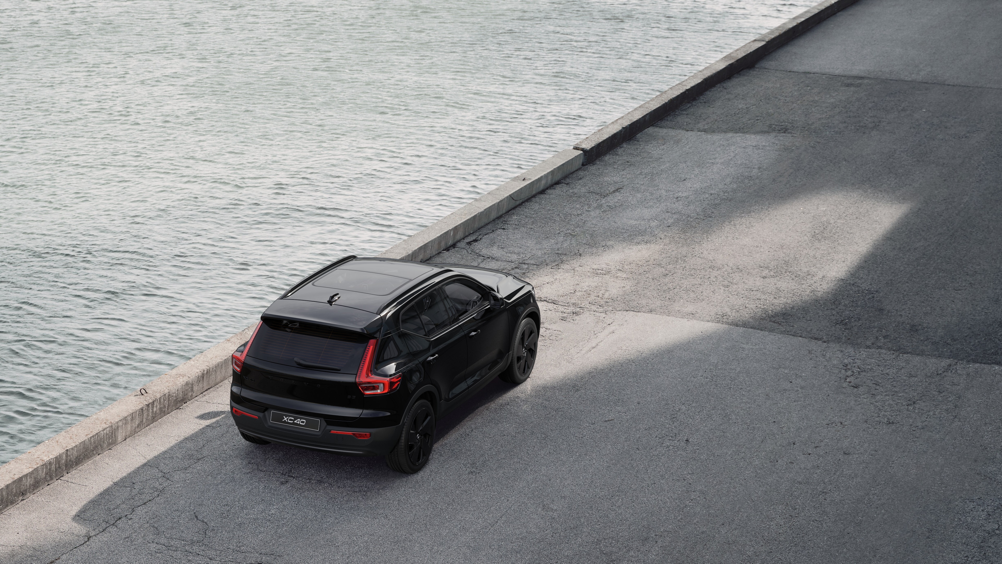 Vue arrière d’une Volvo garée dans une rue calme au bord de l’eau, avec une passerelle pavée et de l’eau en arrière-plan.