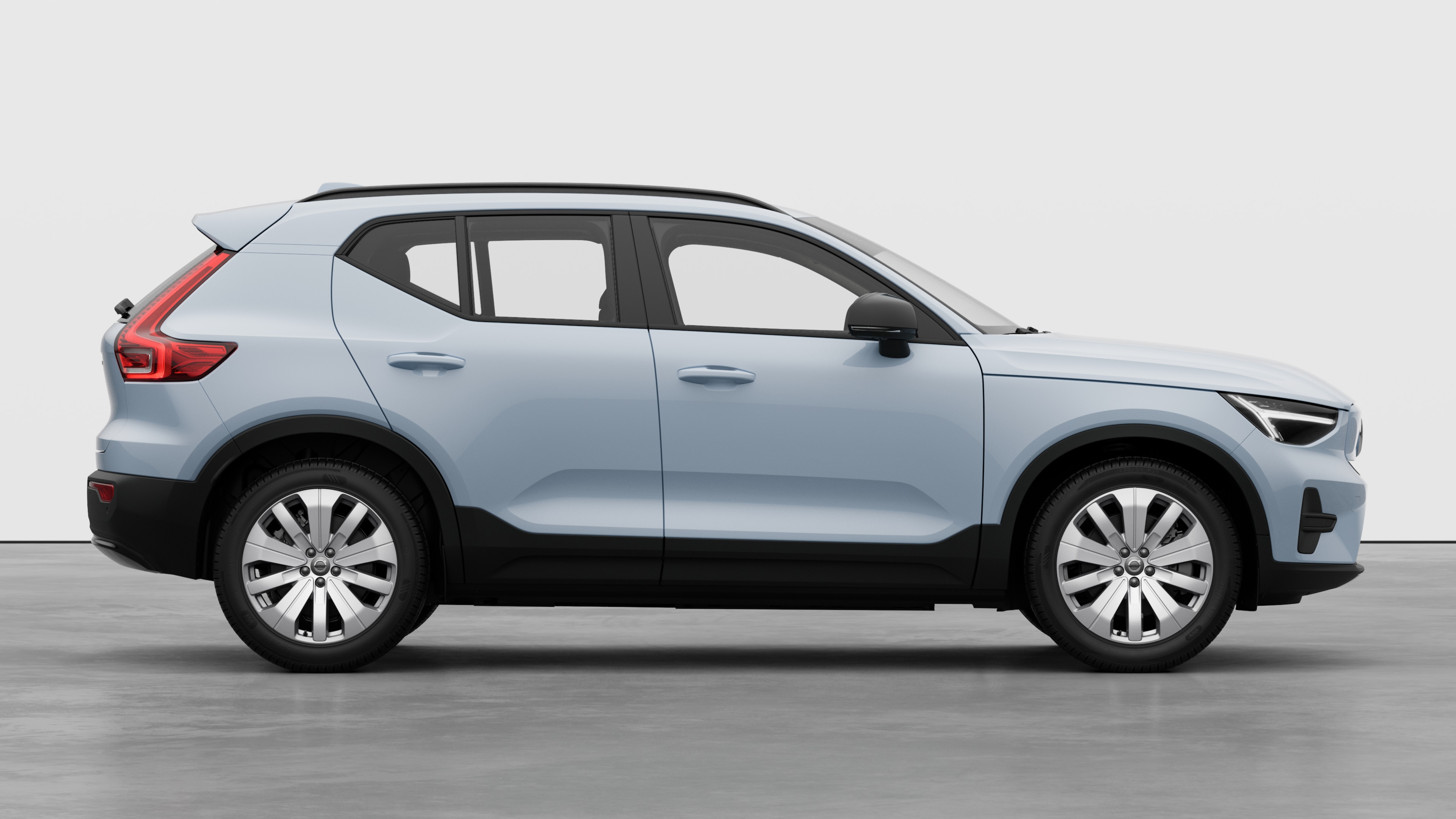 Seitenansicht eines Volvo Fahrzeugs auf einem schlichten Studiohintergrund mit geschlossenen Türen und sichtbarem Raddesign.