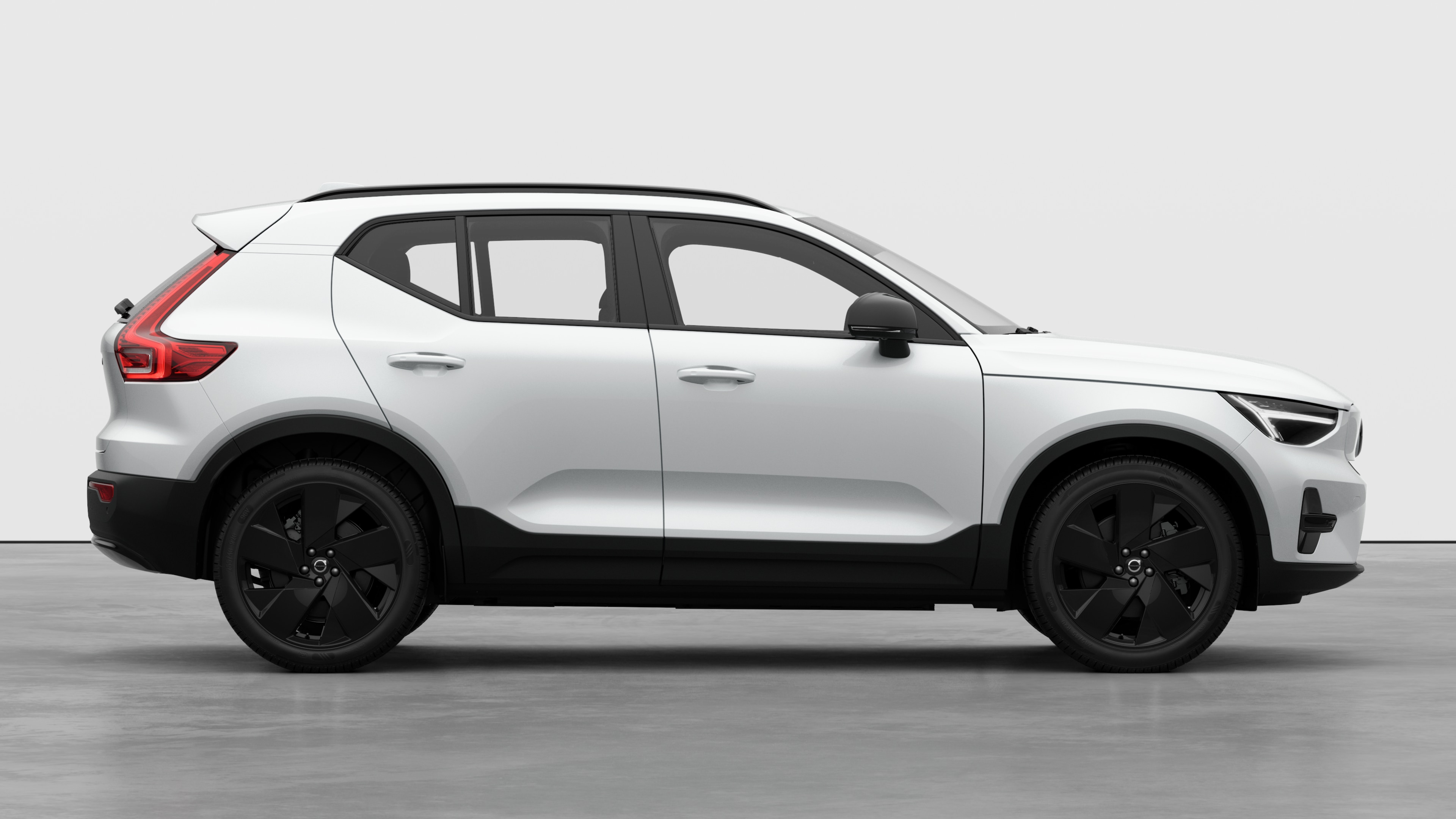 Seitenansicht eines Volvo Fahrzeugs auf einem schlichten Studiohintergrund mit geschlossenen Türen und sichtbarem Raddesign.