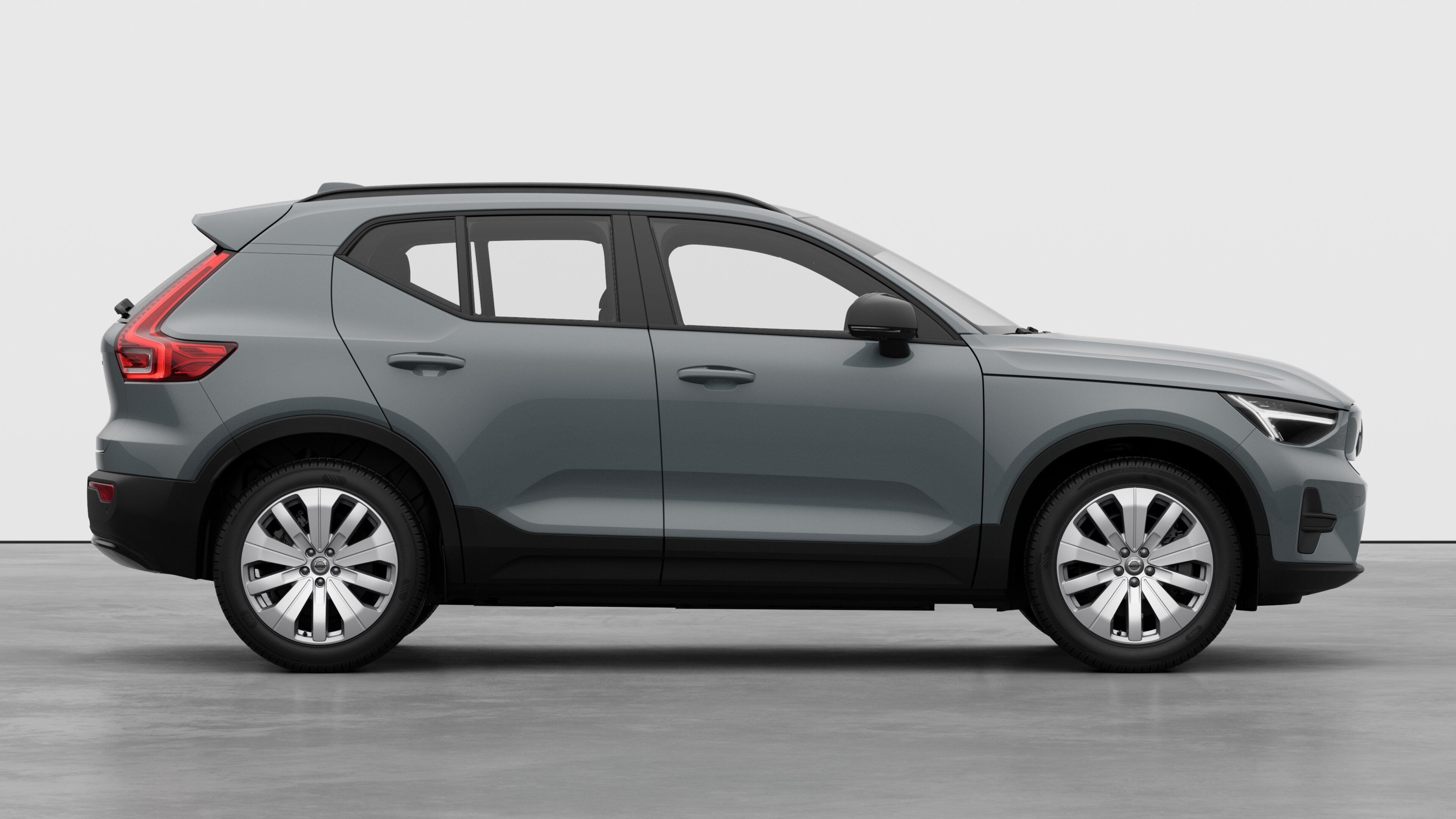 Zijaanzicht van een Volvo op een eenvoudige studioachtergrond met gesloten deuren en zichtbaar wielontwerp.