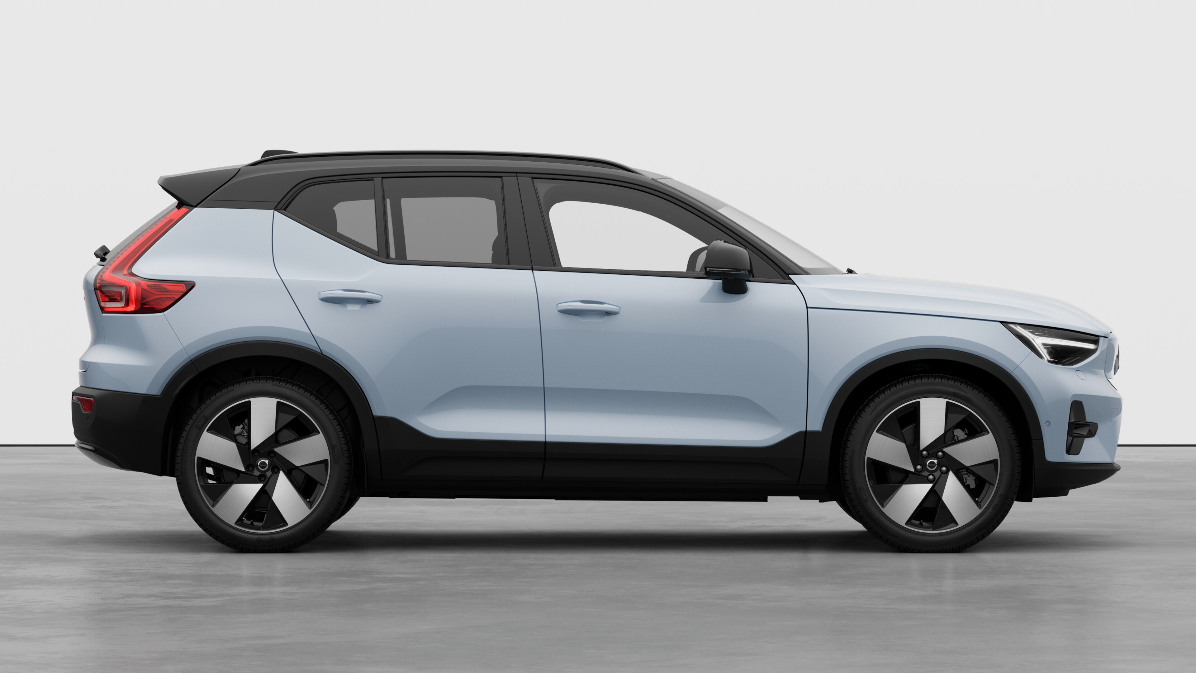 Volvo car side view on plain studio background displaying closed doors and visible wheel design.