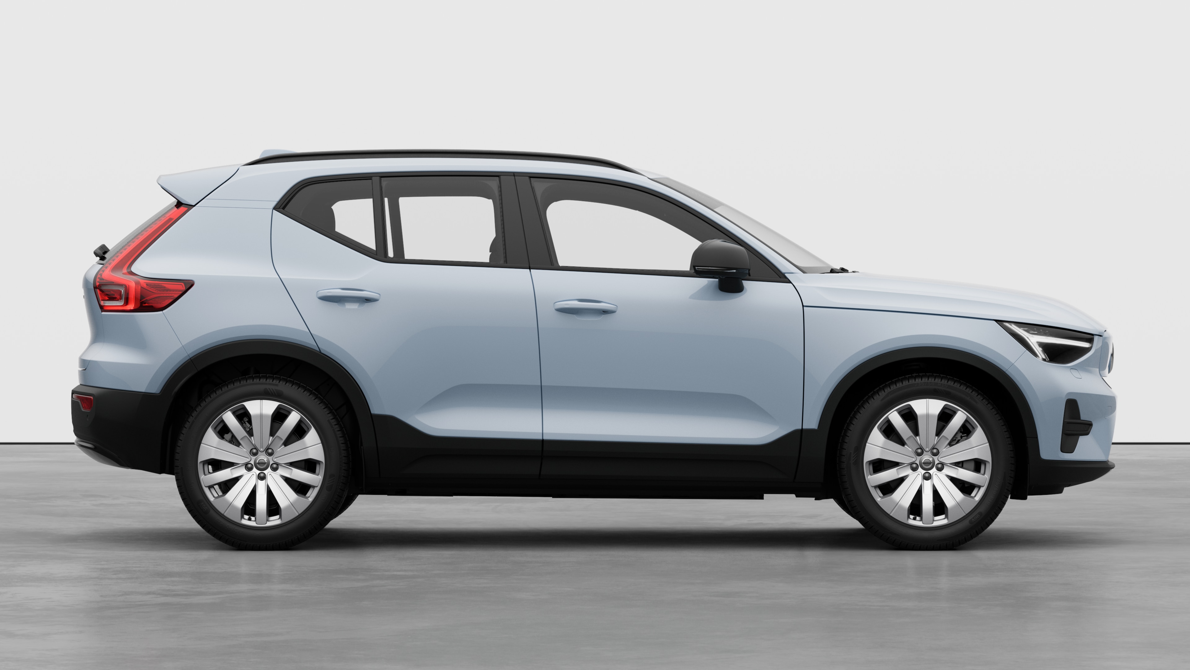 Volvo-bilens sidevisning på vanlig studiobakgrunn som viser lukkede dører og synlig hjuldesign.