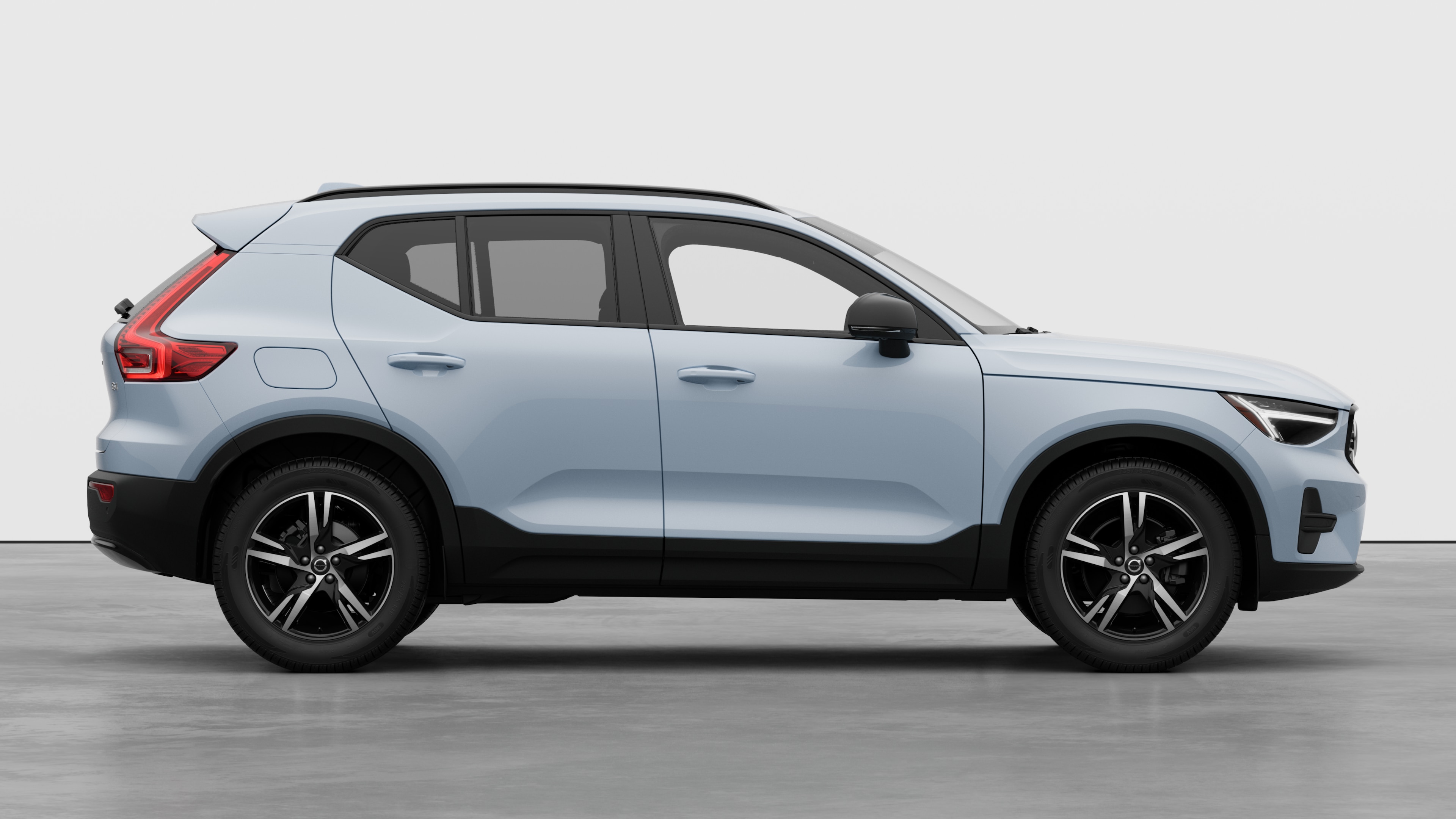 Volvo car side view on plain studio background displaying closed doors and visible wheel design.