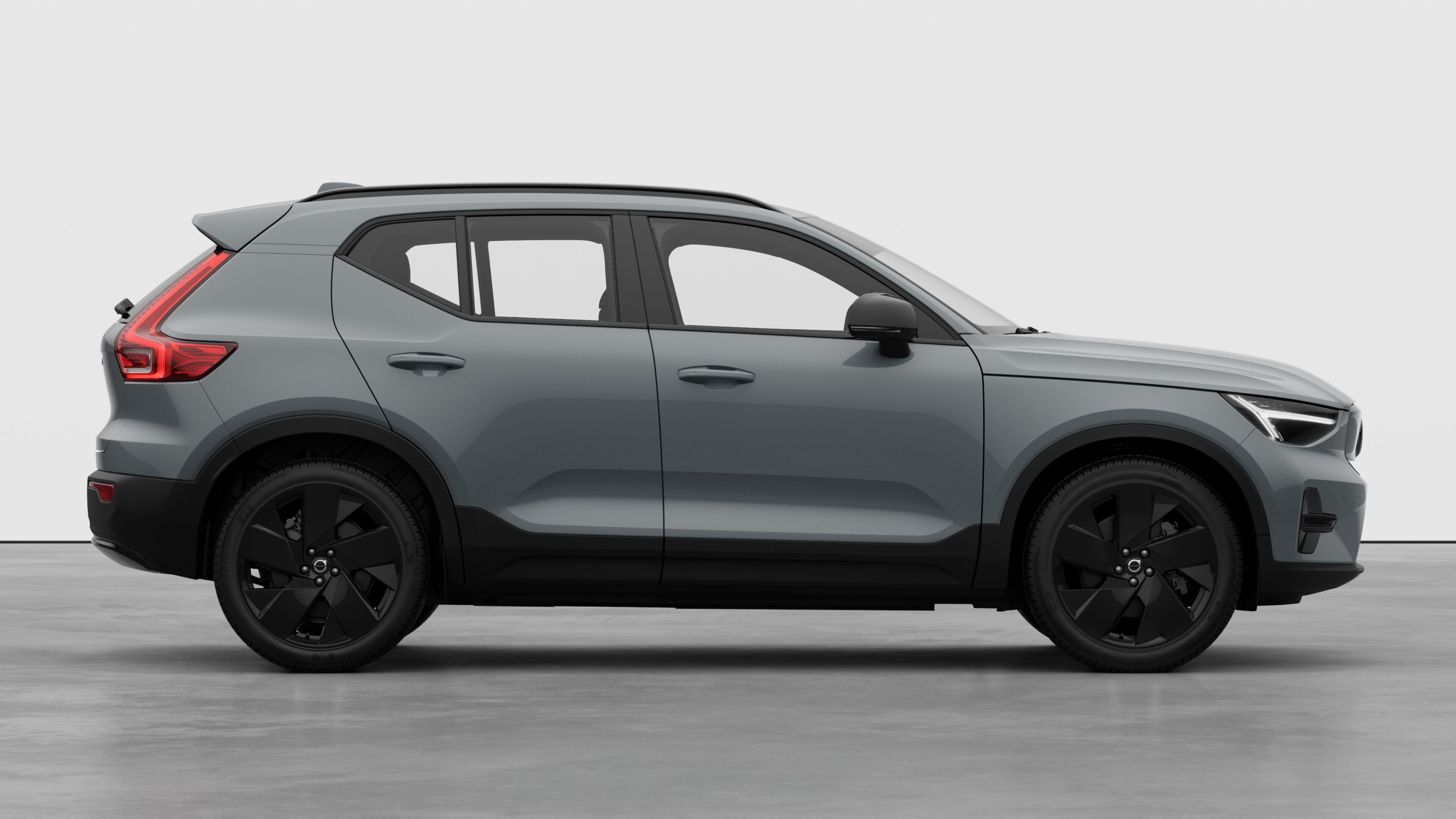 Seitenansicht eines Volvo Fahrzeugs auf einem schlichten Studiohintergrund mit geschlossenen Türen und sichtbarem Raddesign.