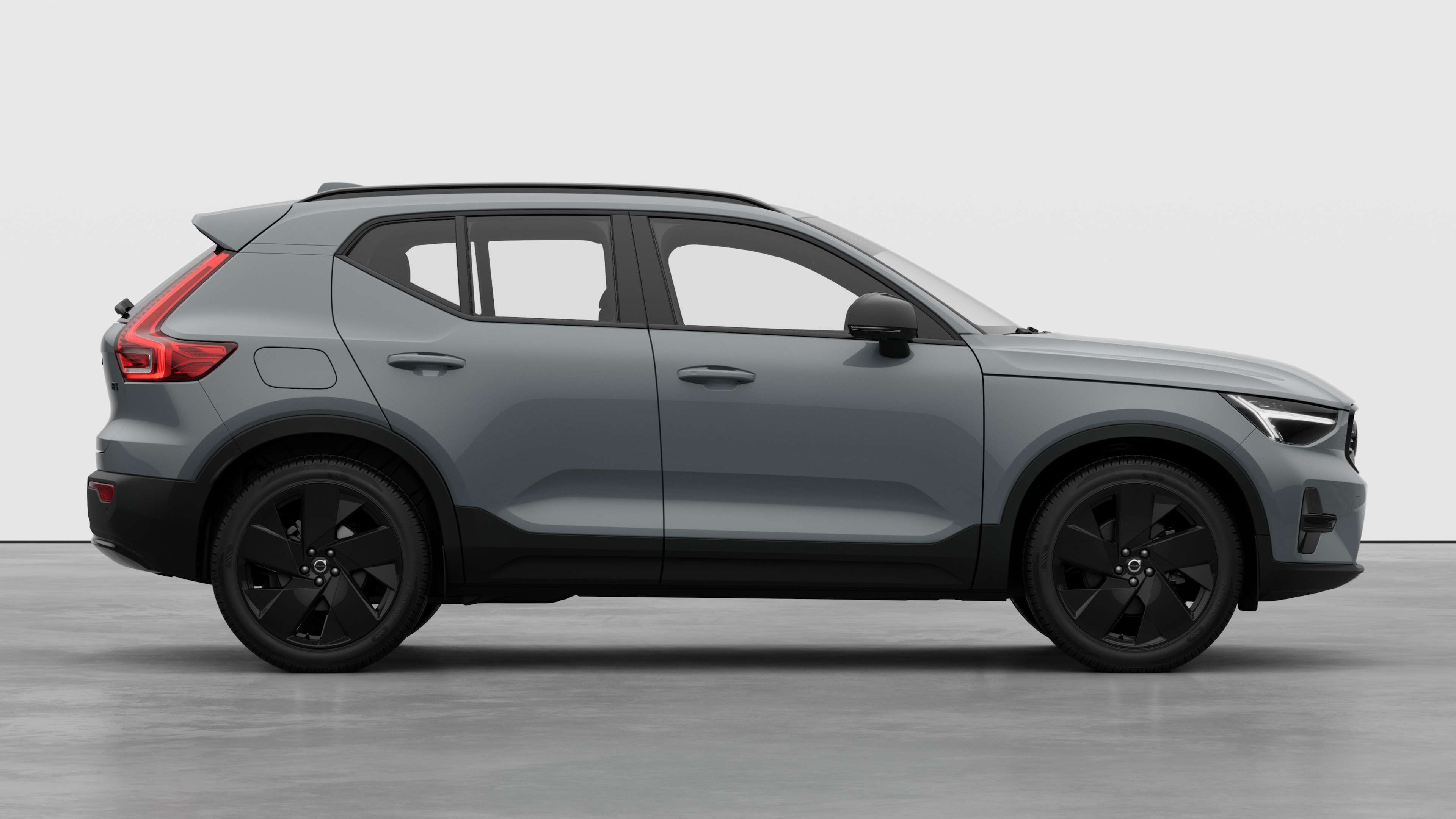 Seitenansicht eines Volvo Fahrzeugs auf einem schlichten Studiohintergrund mit geschlossenen Türen und sichtbarem Raddesign.
