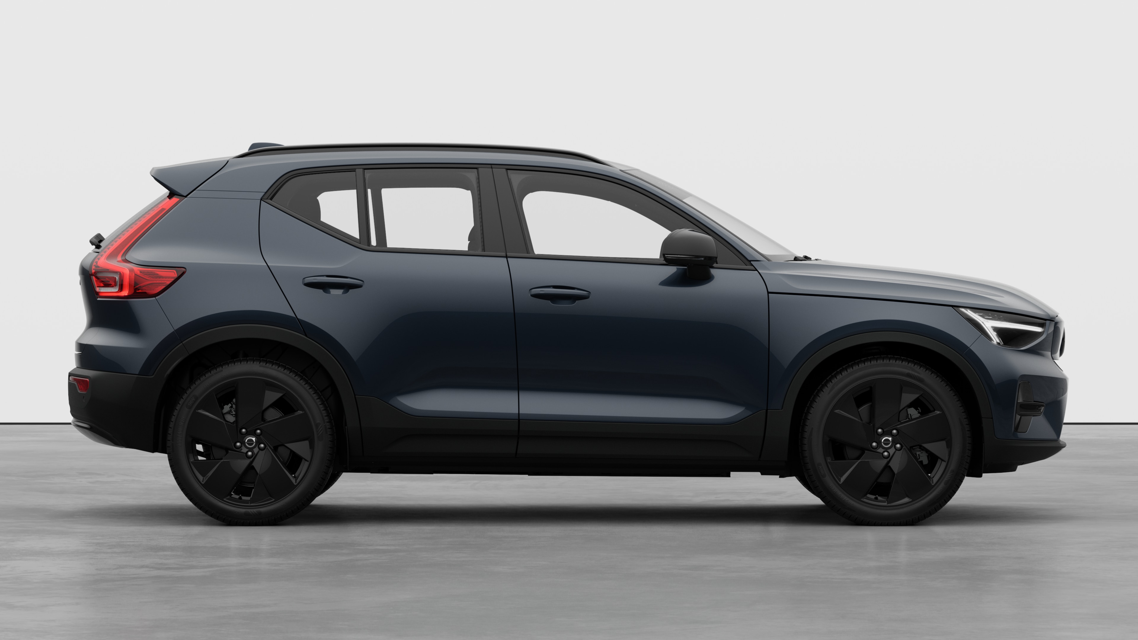 Seitenansicht eines Volvo Fahrzeugs auf einem schlichten Studiohintergrund mit geschlossenen Türen und sichtbarem Raddesign.