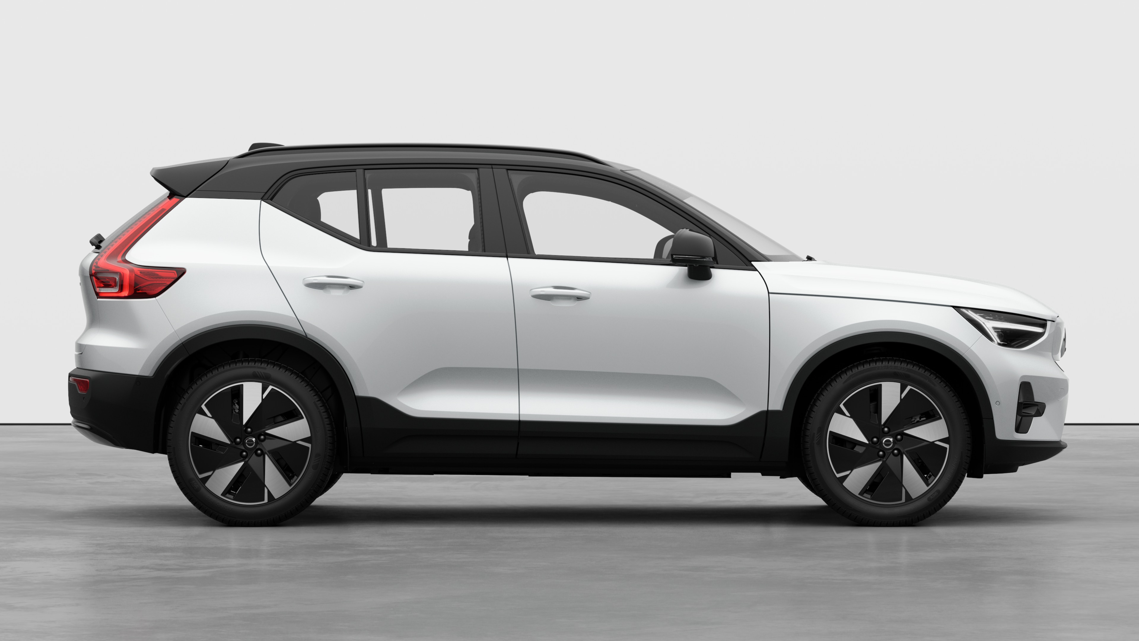 Volvo car side view on plain studio background displaying closed doors and visible wheel design.