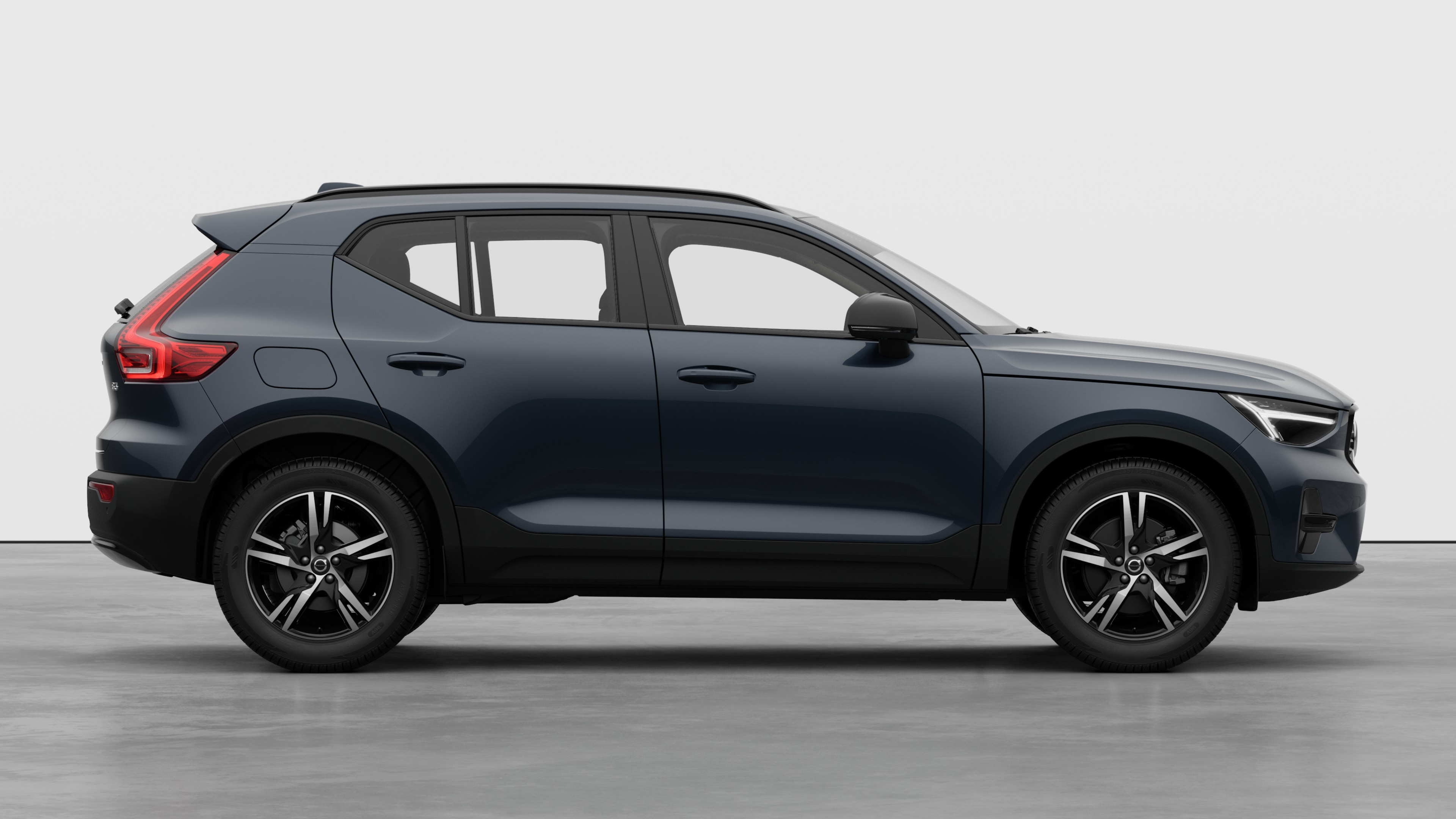 Vue latérale d’une Volvo sur un fond de studio uni, montrant les portes fermées et le design des roues visibles.