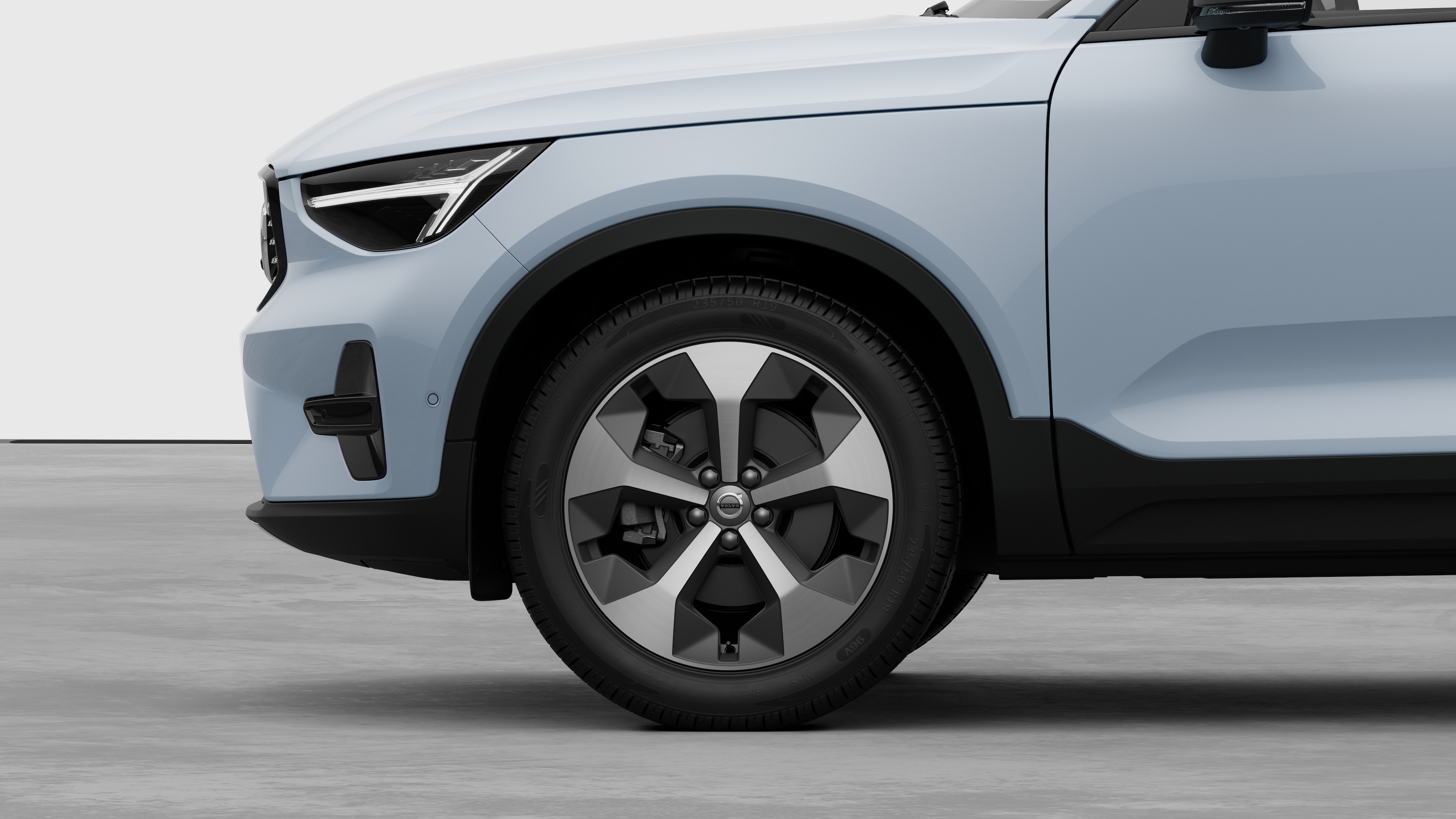 Екстер'єр автомобіля Volvo з акцентом на передньому колесі та крилі на однотонному студійному тлі.