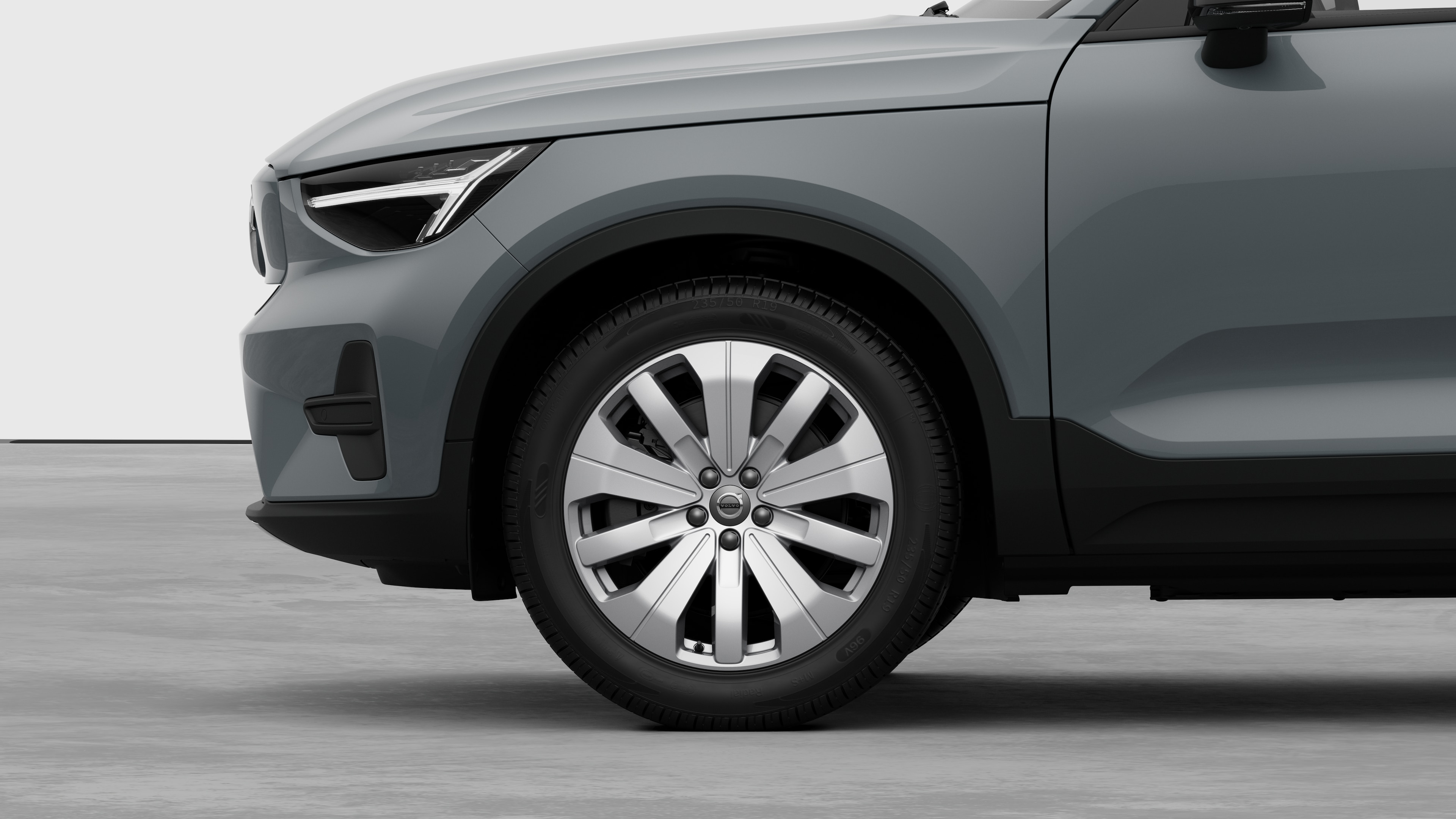 Vue latérale extérieure de la Volvo se concentrant sur la roue avant et l’aile, sur un fond de studio uni.