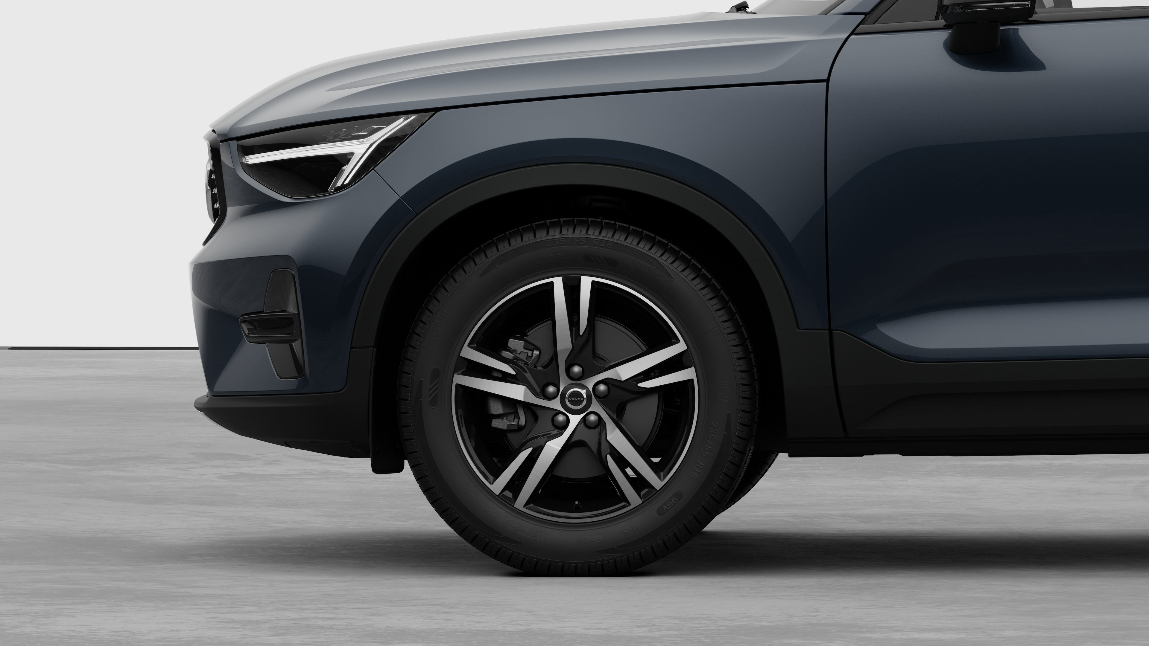 Vue latérale de l’extérieur d’une Volvo se concentrant sur la roue avant et l’aile, sur un fond de studio uni.