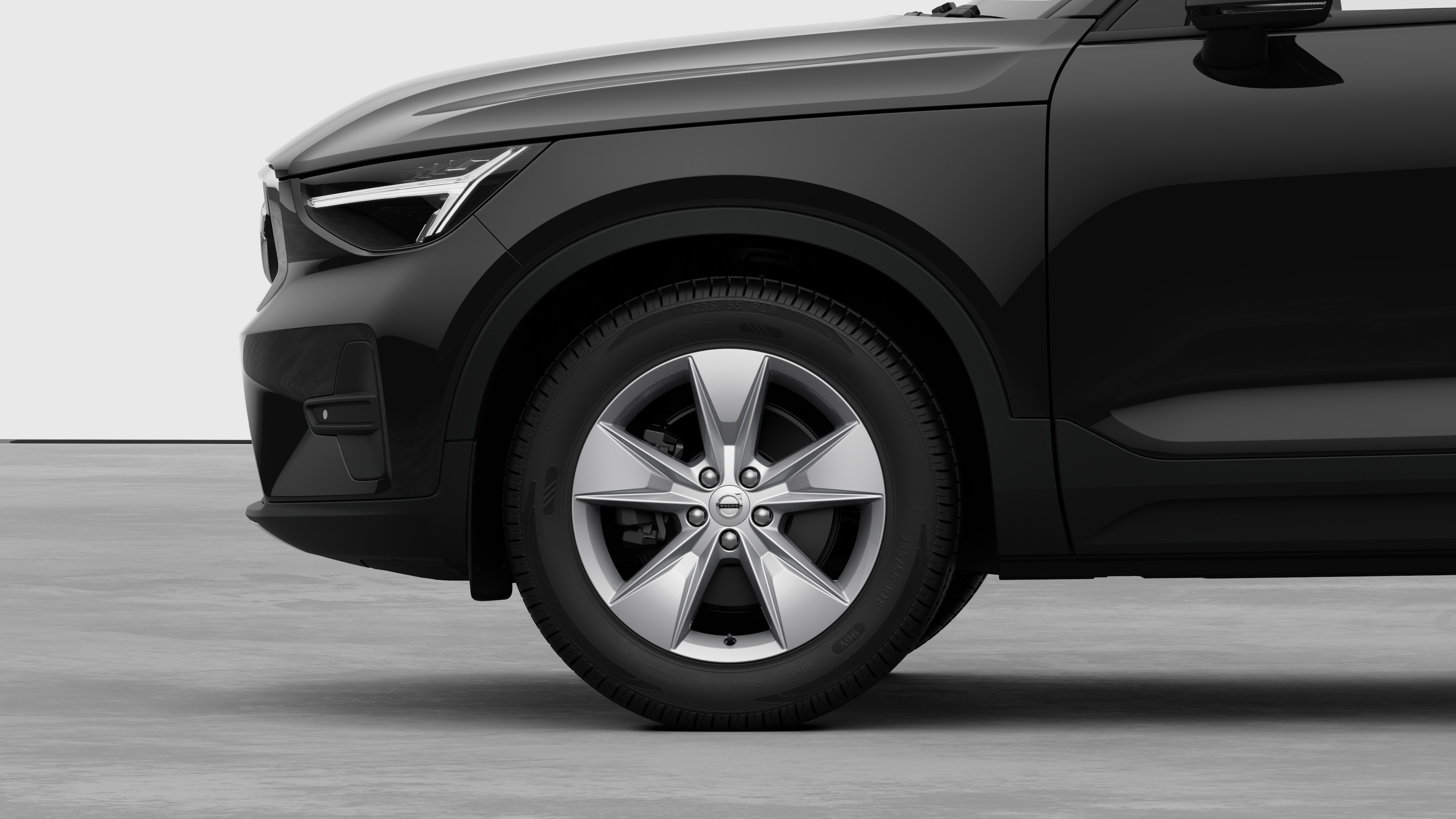 Volvo car exterior side view focusing on the front wheel and fender, set against a plain studio background.