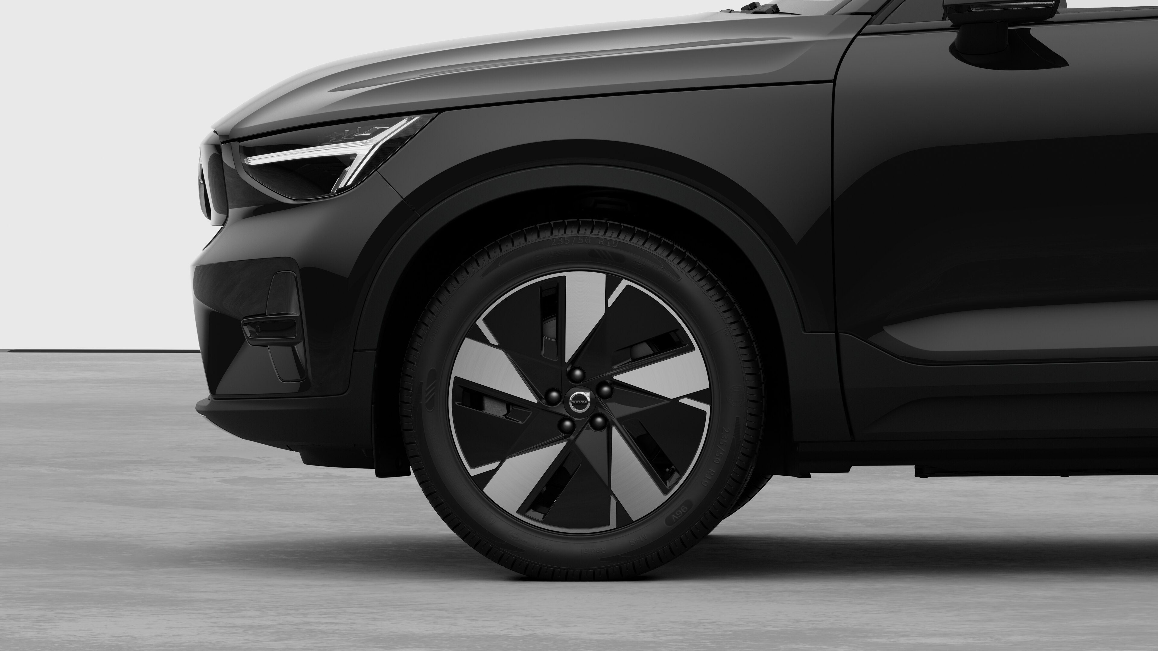 Volvo car exterior side view focusing on the front wheel and fender, set against a plain studio background.