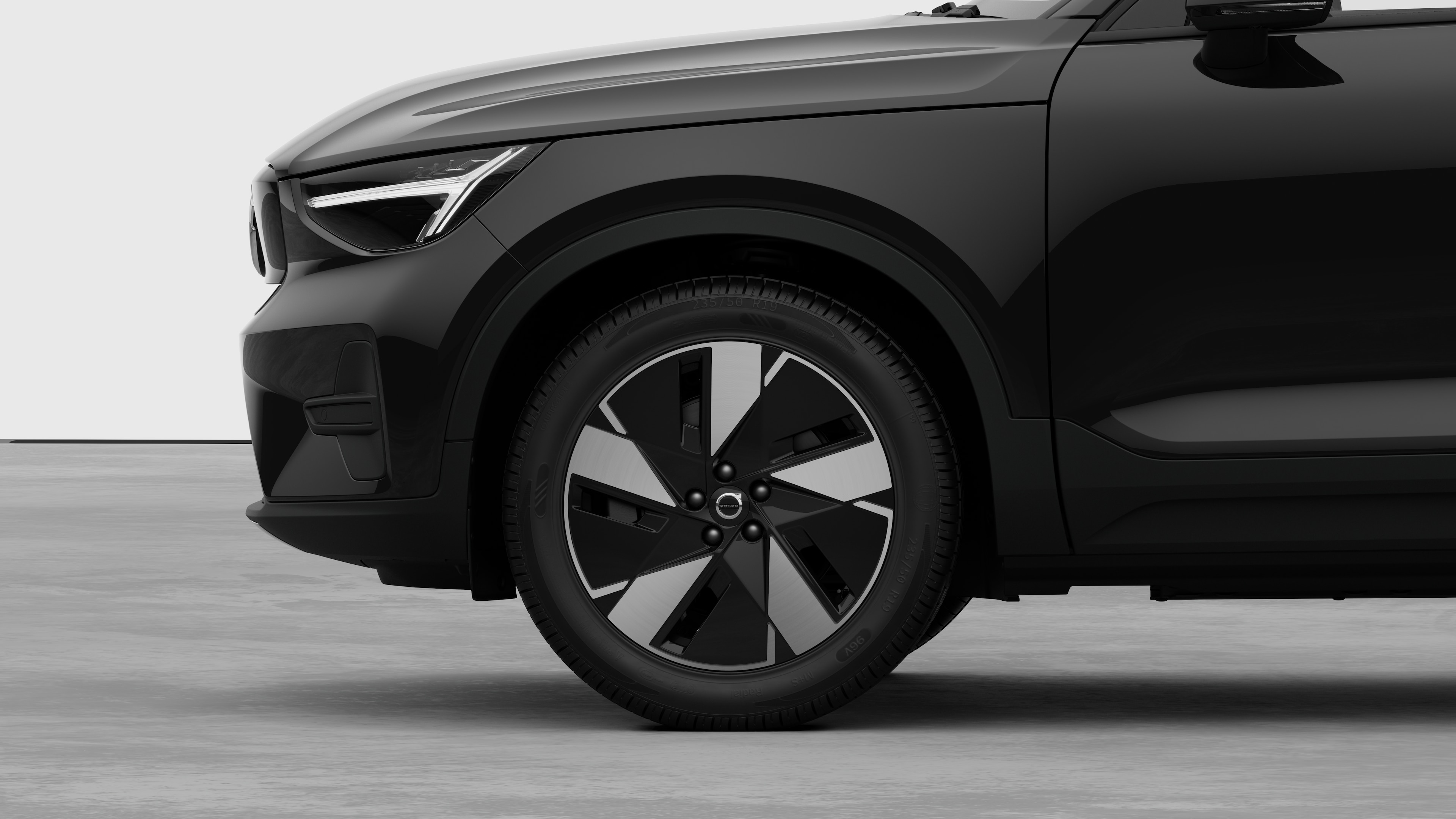 Volvo car exterior side view focusing on the front wheel and fender, set against a plain studio background.