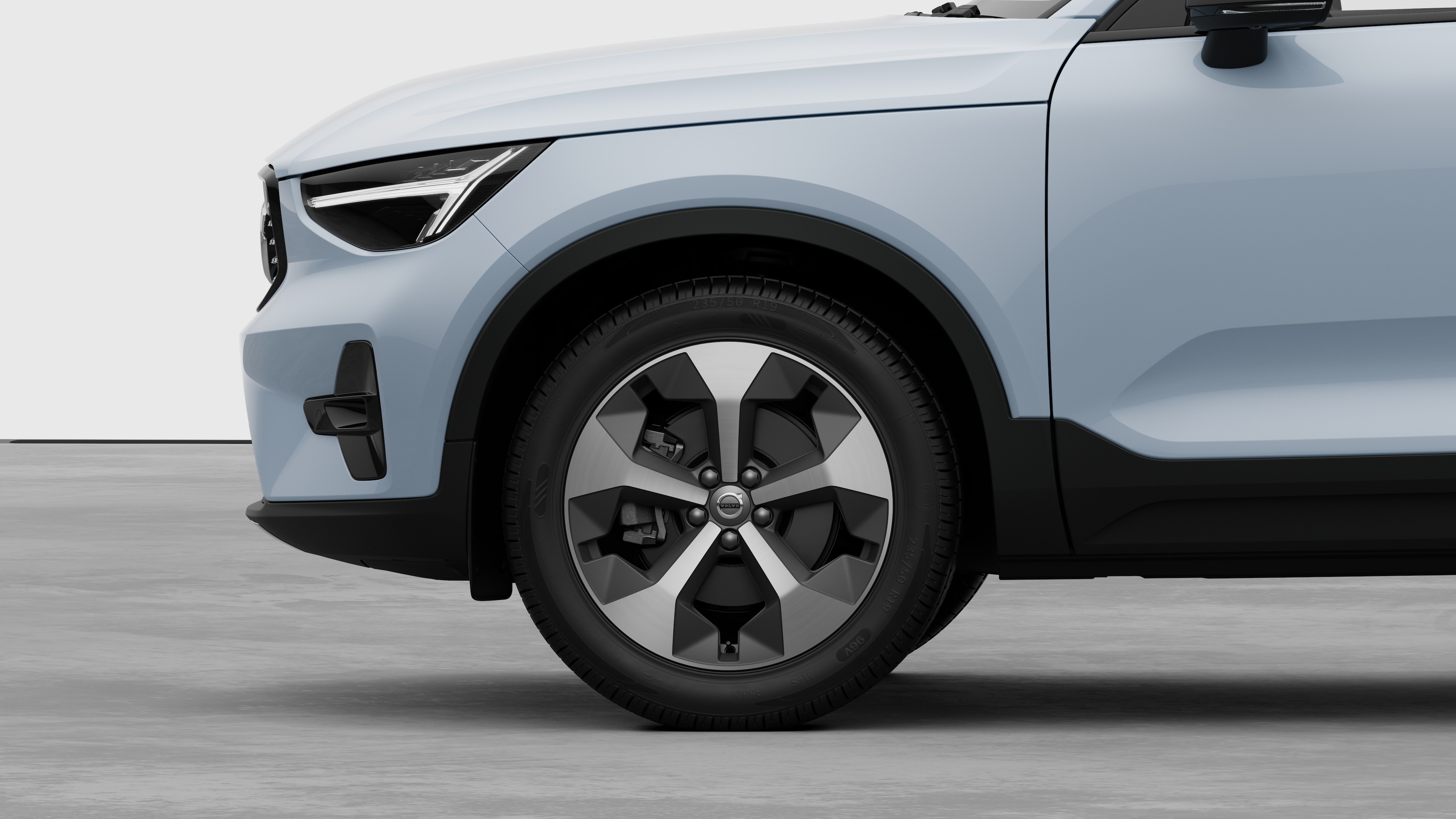 Volvo car exterior side view focusing on the front wheel and fender, set against a plain studio background.