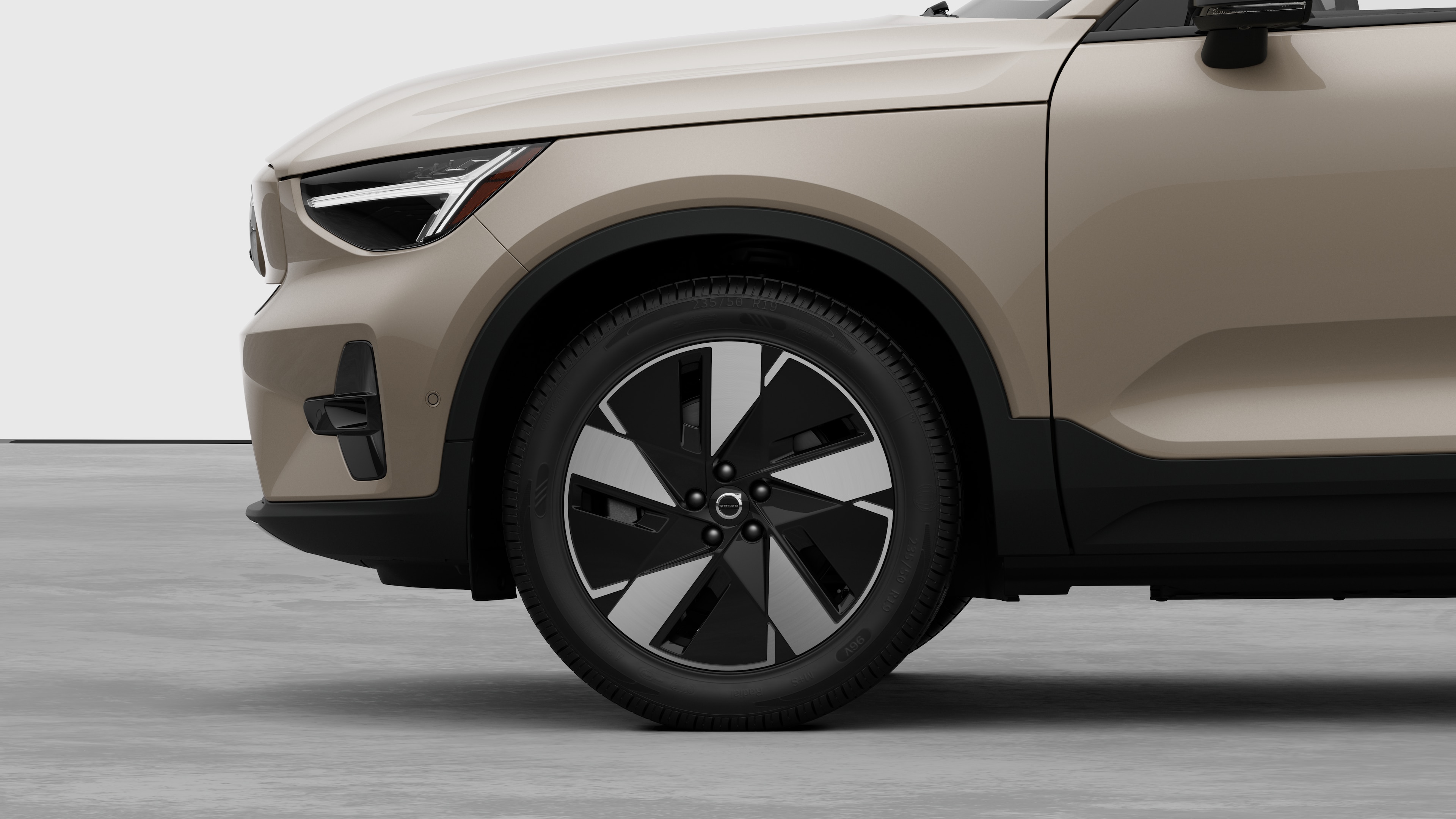 Volvo car exterior side view focusing on the front wheel and fender, set against a plain studio background.