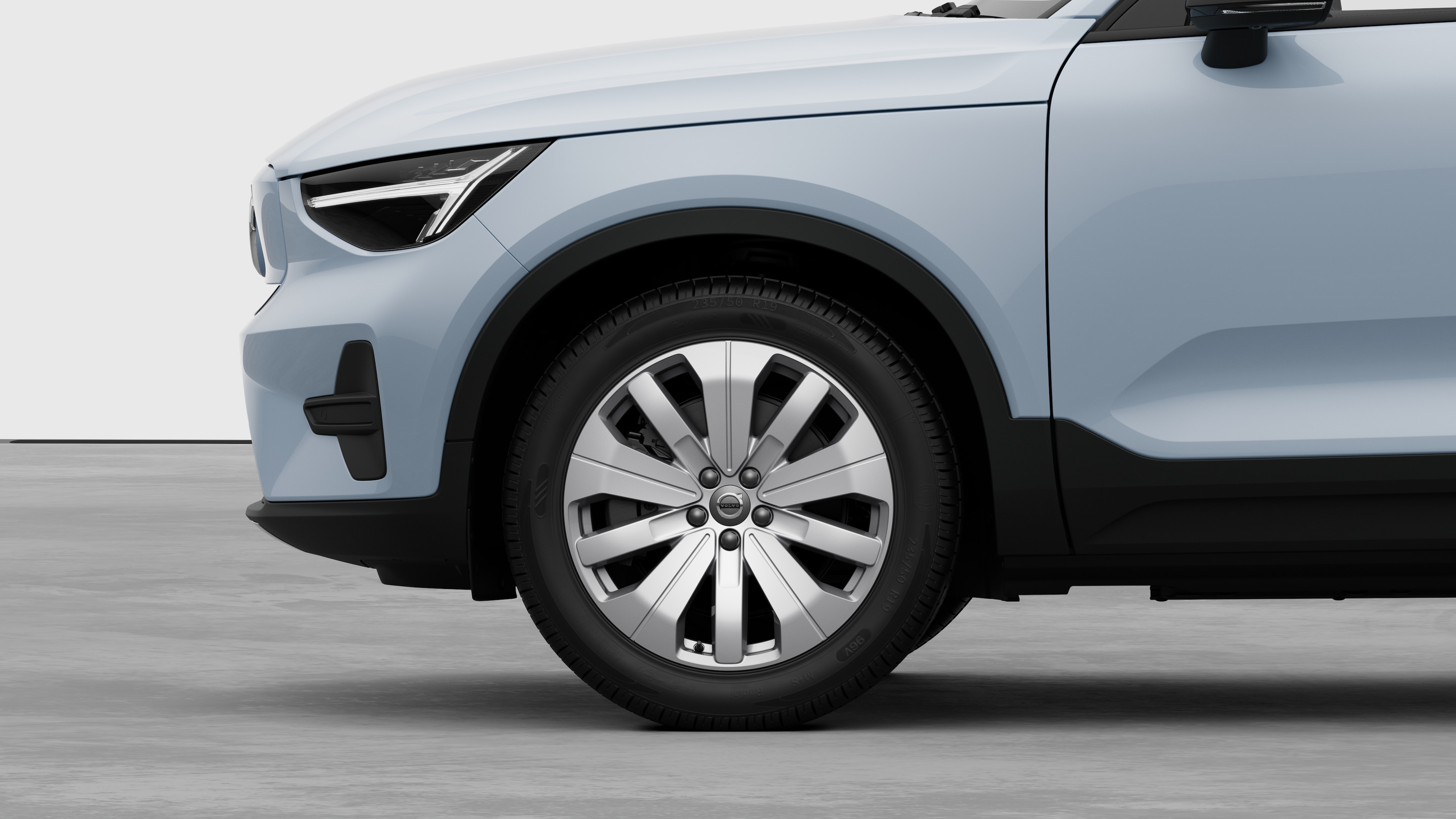 Volvo car exterior side view focusing on the front wheel and fender, set against a plain studio background.