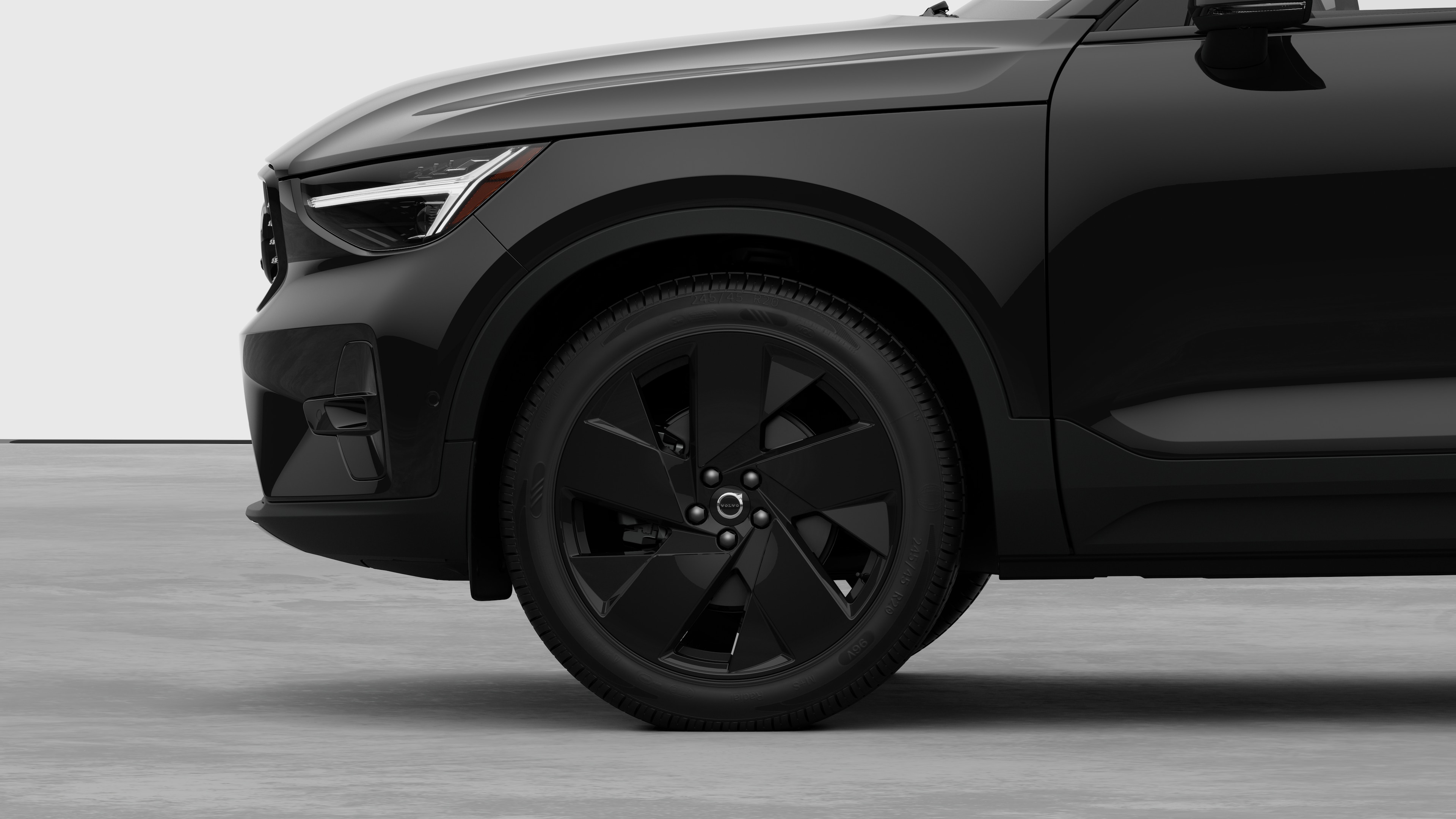 Volvo car exterior side view focusing on the front wheel and fender, set against a plain studio background.