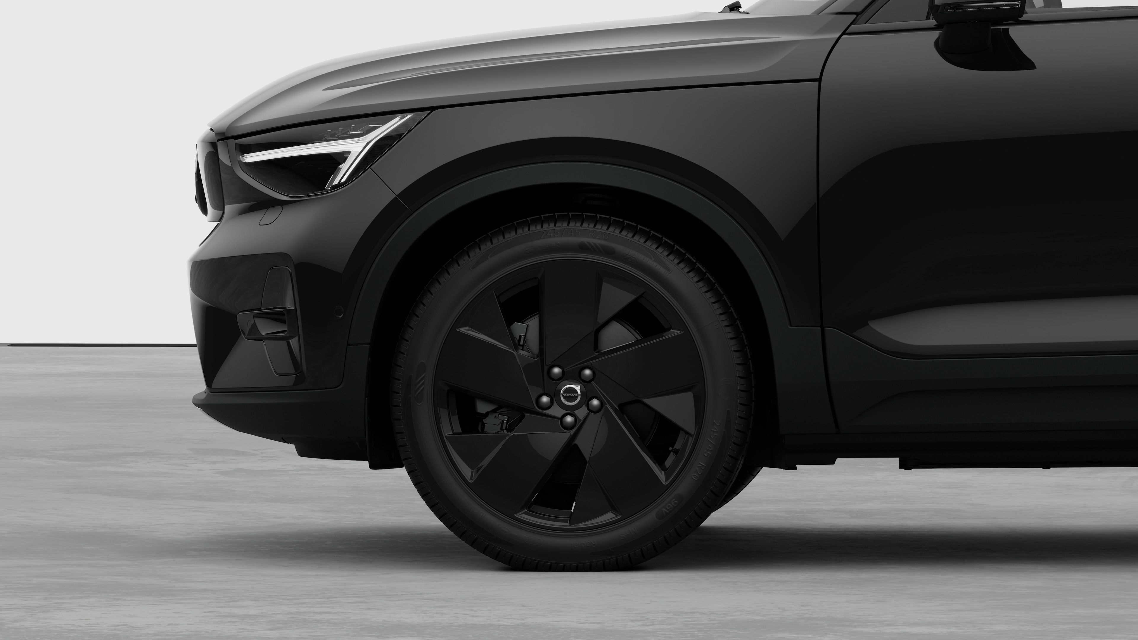 Volvo-bilens udvendige sidebillede med fokus på forhjulet og skærmen, sat op mod en almindelig studiebaggrund.