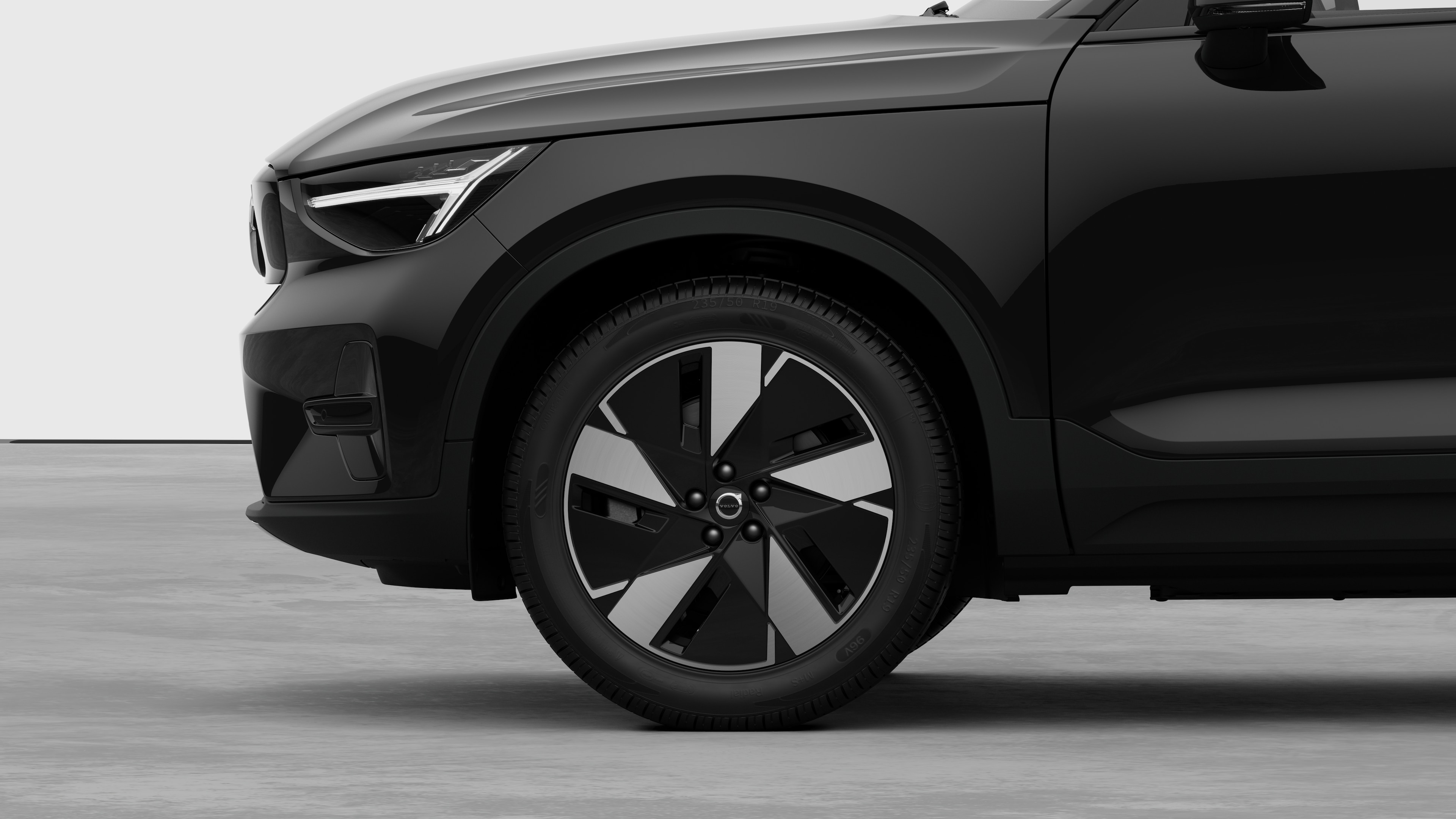 Vista lateral exterior del vehículo Volvo centrada en la rueda delantera y el guardabarros, sobre un fondo de estudio liso.