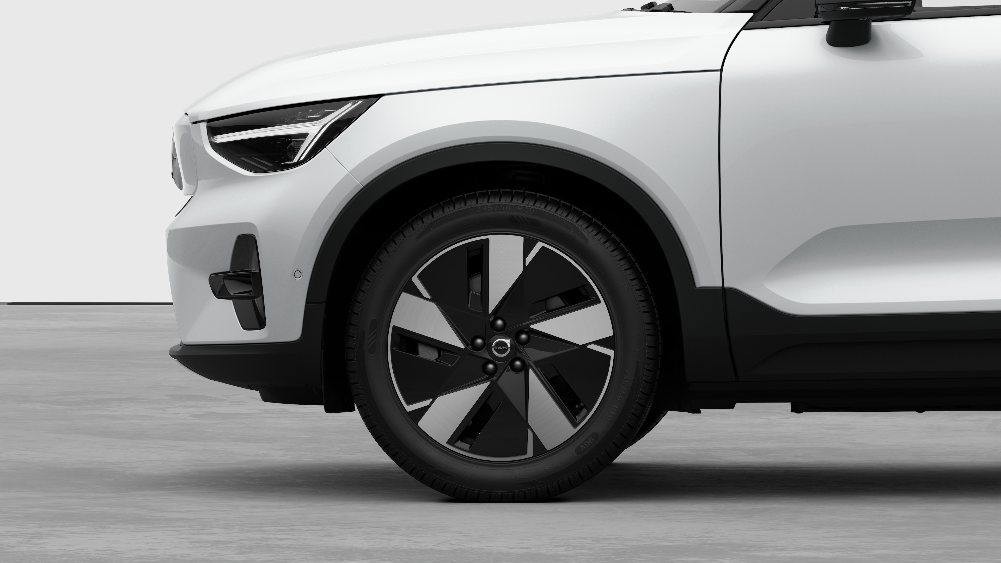 Volvo car exterior side view focusing on the front wheel and fender, set against a plain studio background.