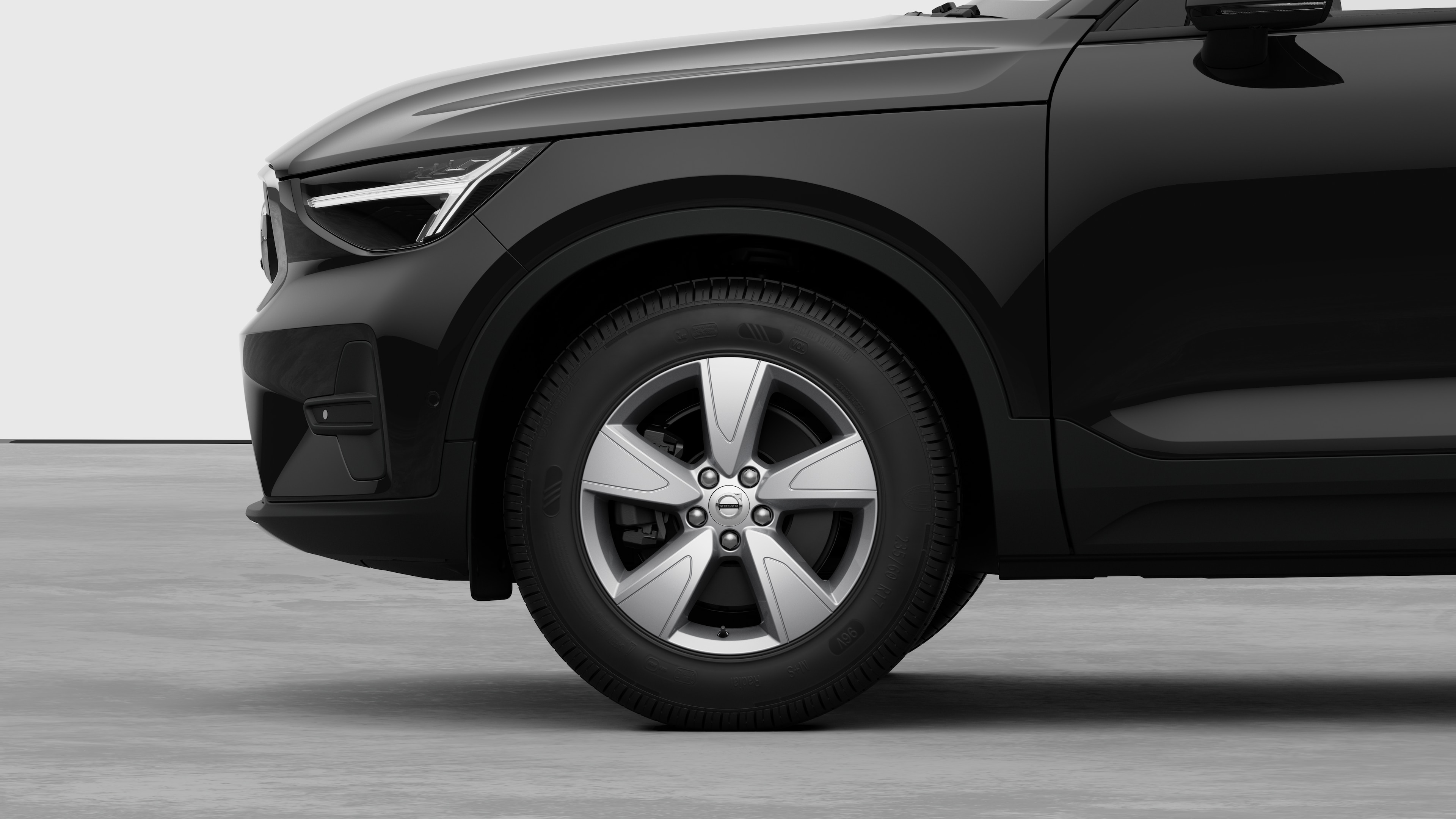 無地のスタジオを背景に、フロントホイールとフェンダーに焦点を合わせたボルボ車のエクステリアサイドビュー。