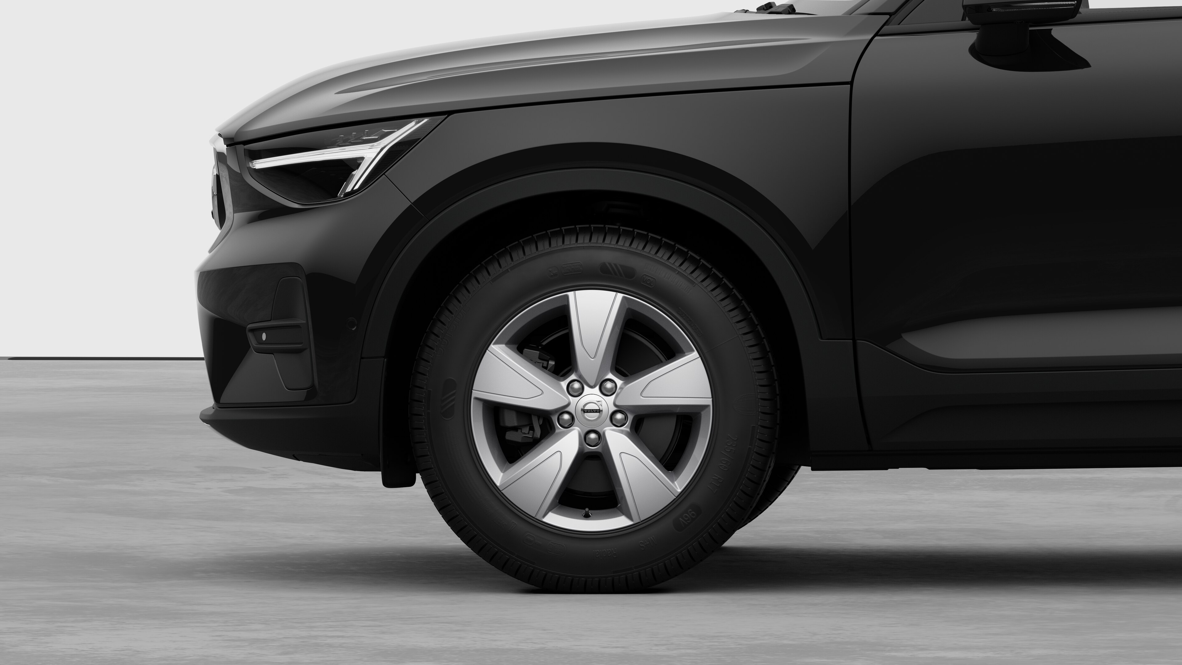 無地のスタジオを背景に、フロントホイールとフェンダーに焦点を合わせたボルボ車のエクステリアサイドビュー。