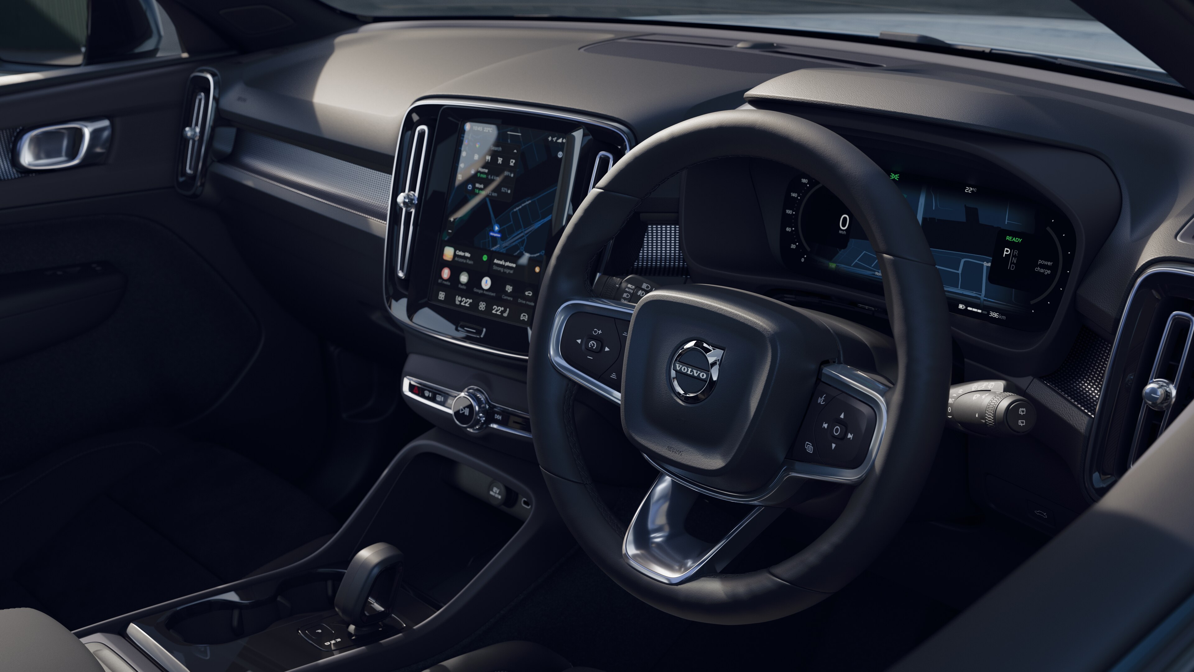 Volvo car interior showing dashboard, steering wheel, and center console with digital display in an open road background.