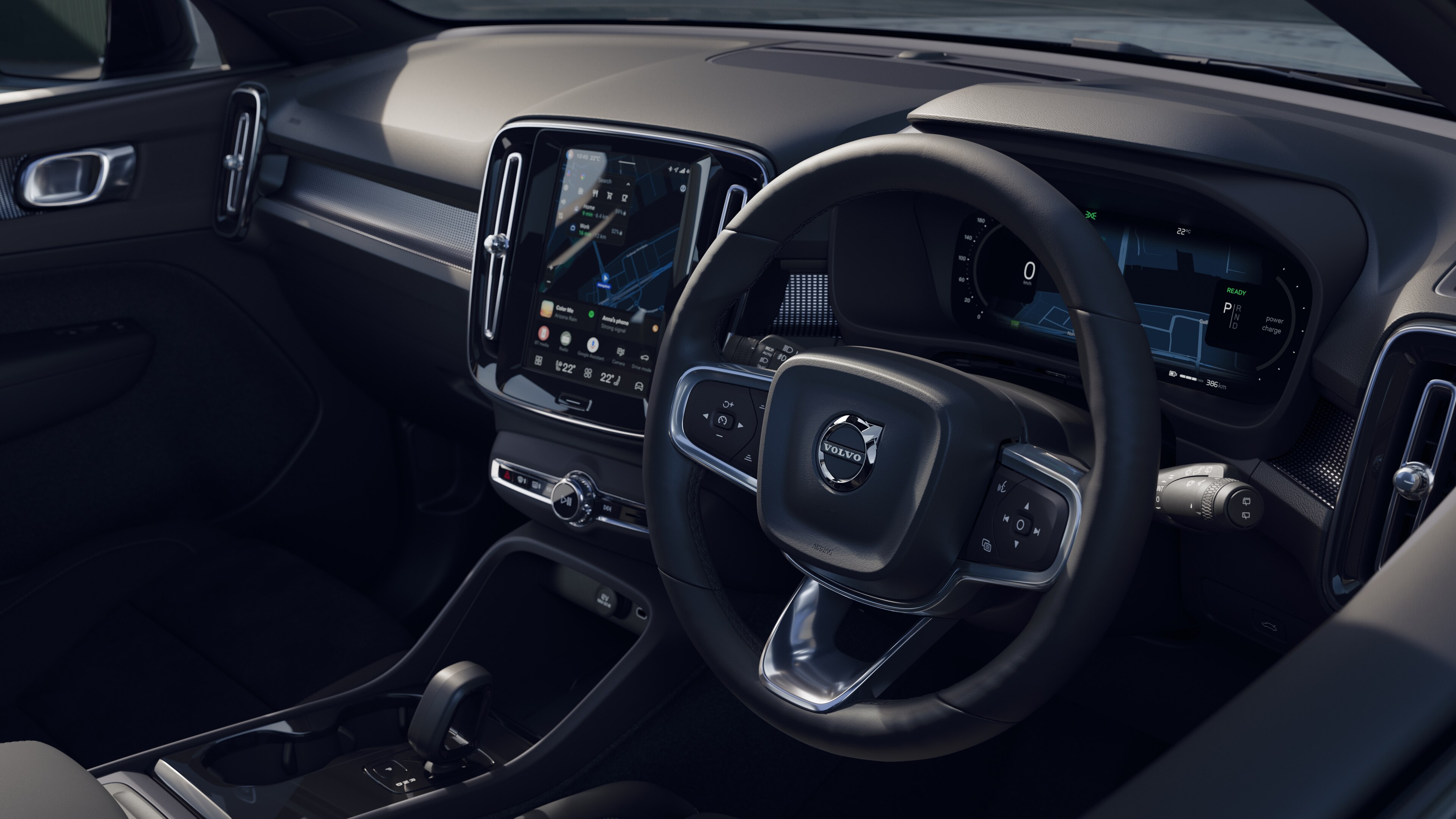 Volvo car interior showing dashboard, steering wheel, and center console with digital display in an open road background.